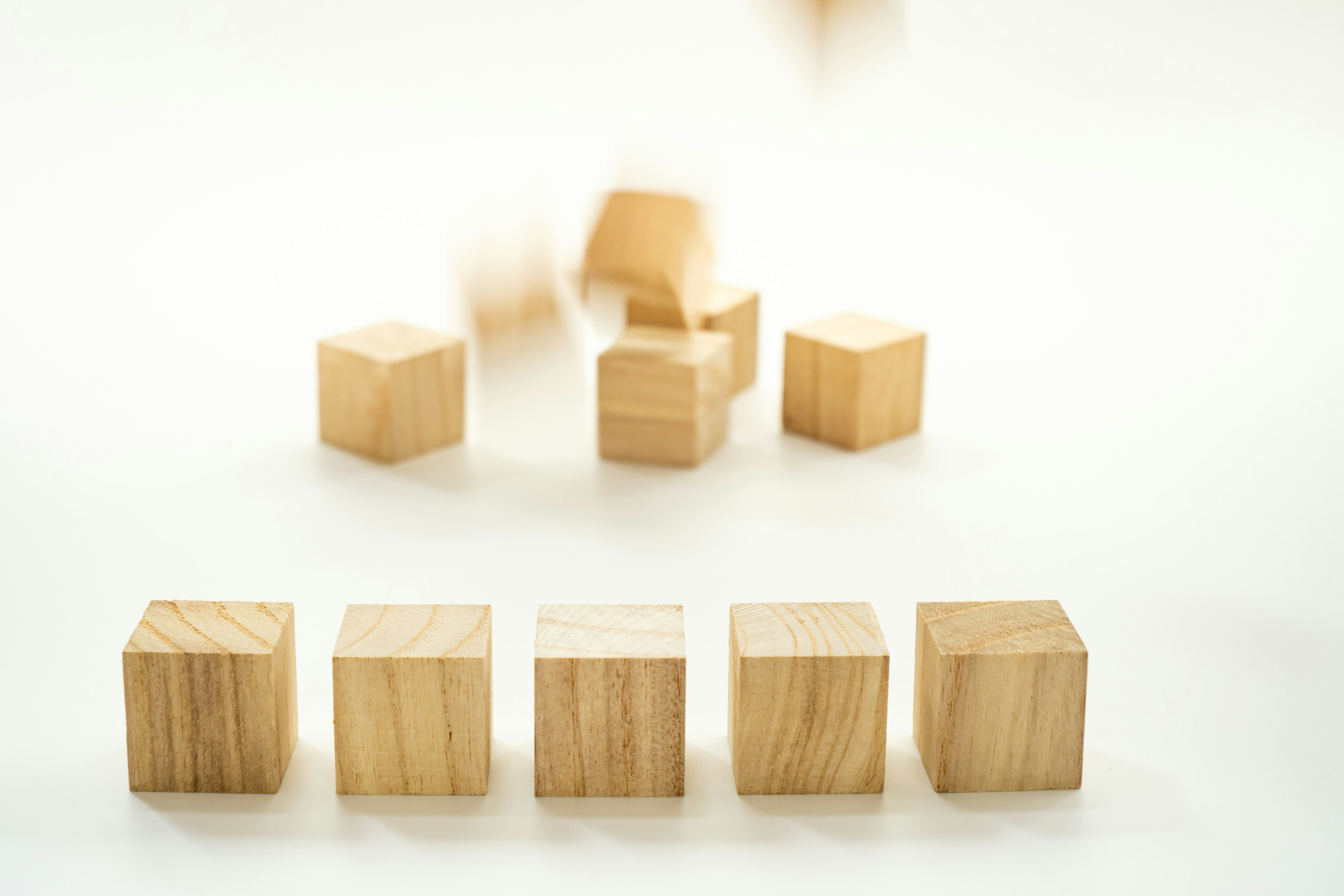 Image of wooden cubes arranged in a row with several cubes in motion in the background