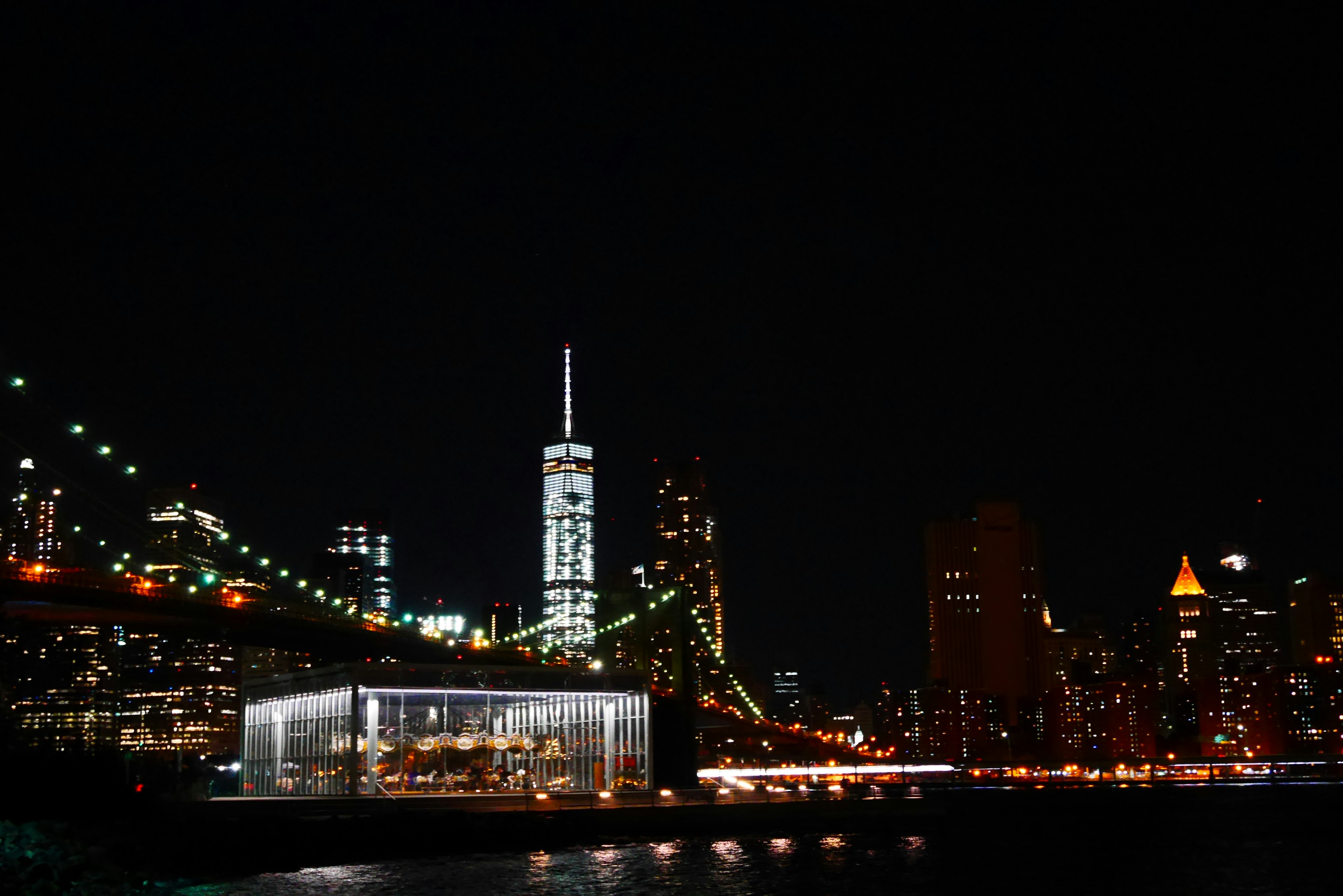 New York City skyline at night featuring illuminated buildings and a bridge