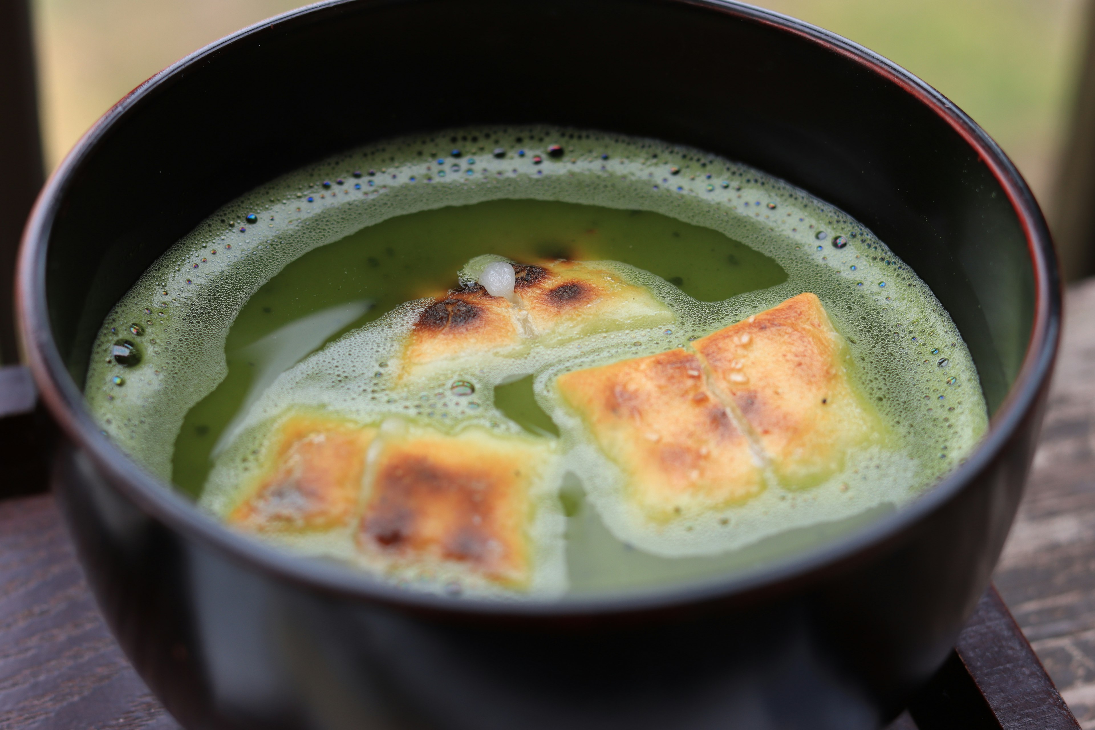 Bowl of green tea with toasted mochi