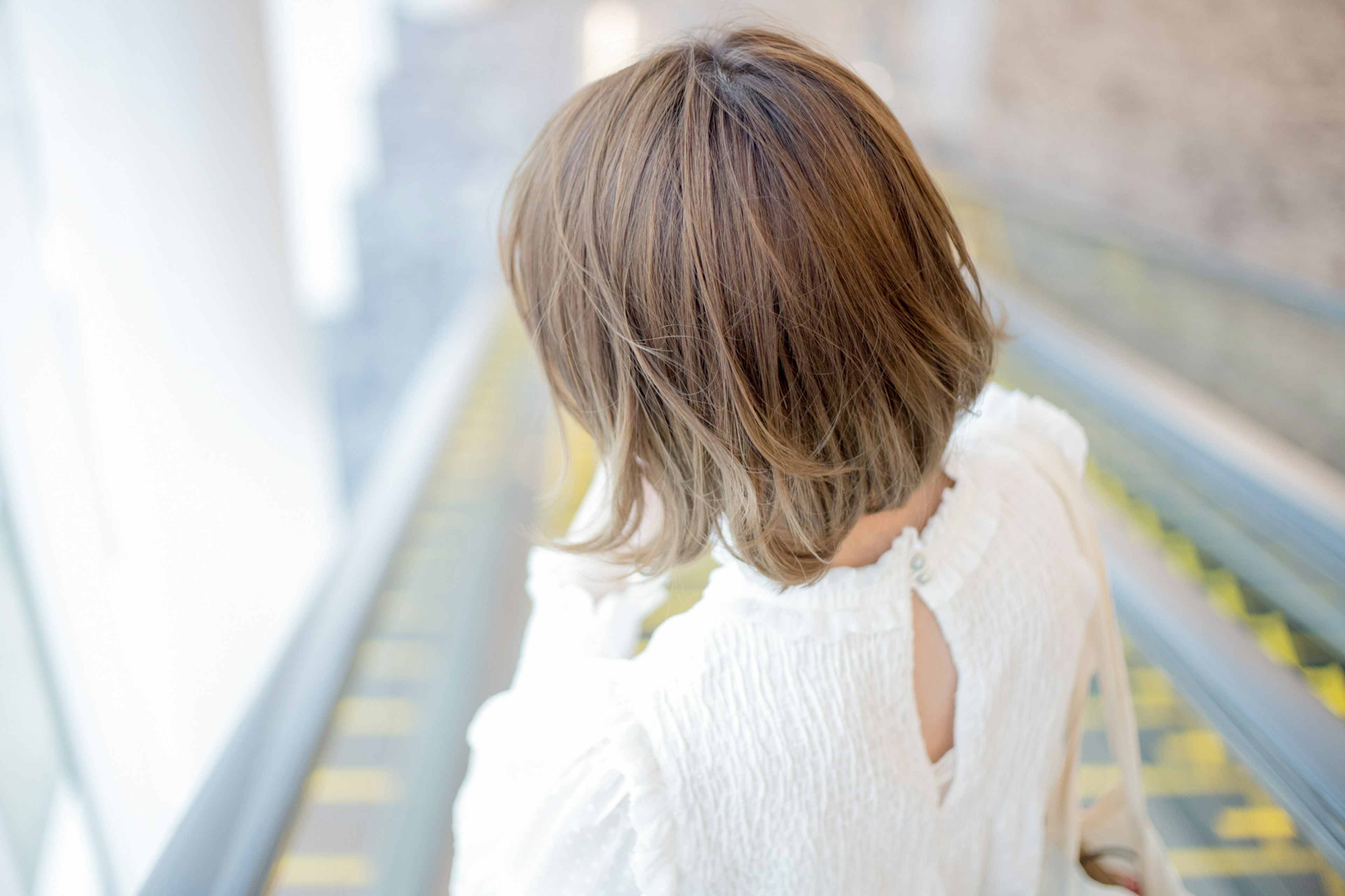 Frau, die Treppen hinuntergeht mit einem kurzen Bob-Haarschnitt Helles Licht strömt in den Raum