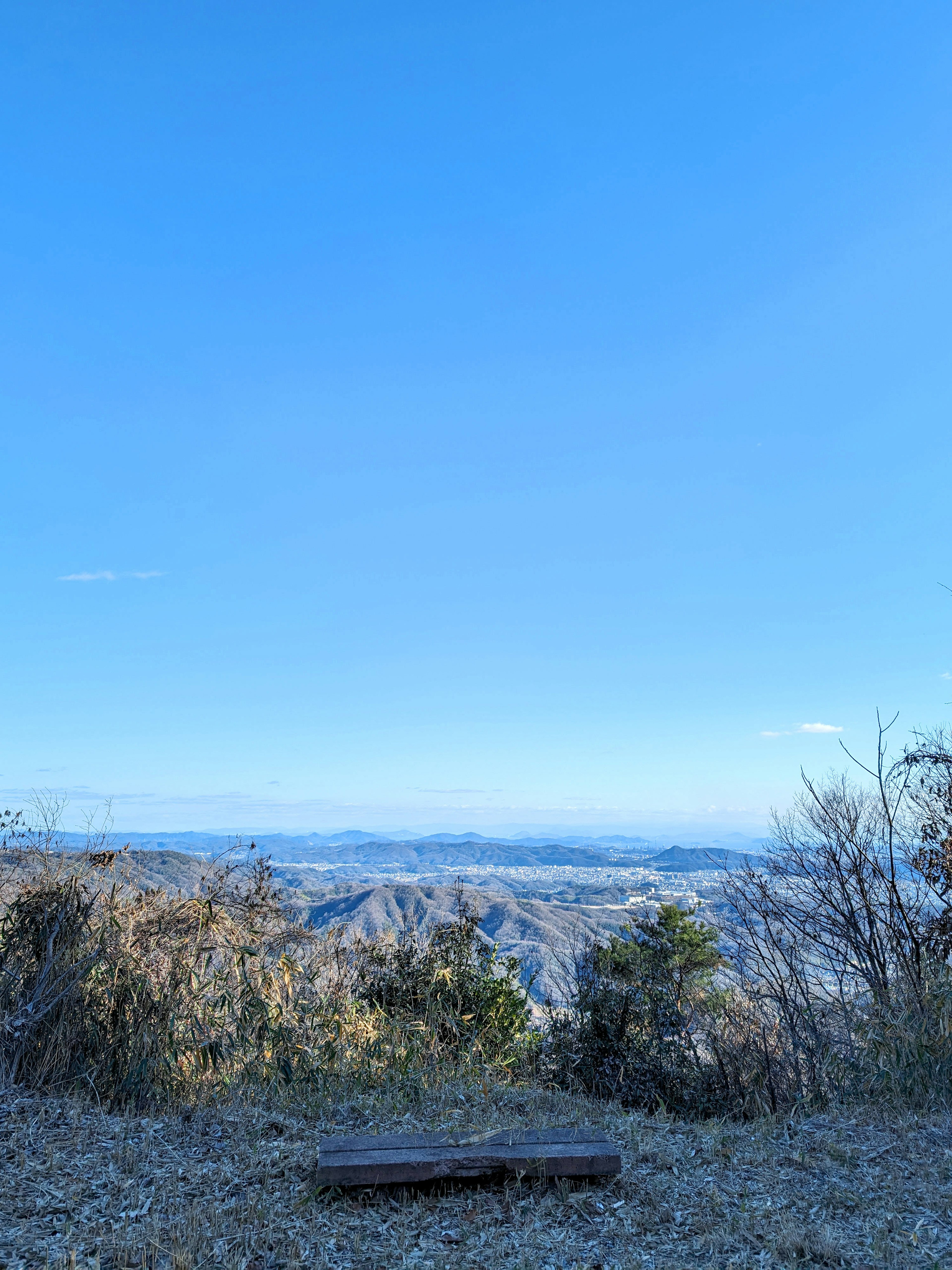 Una panchina di legno con vista su un vasto paesaggio montano e un cielo azzurro