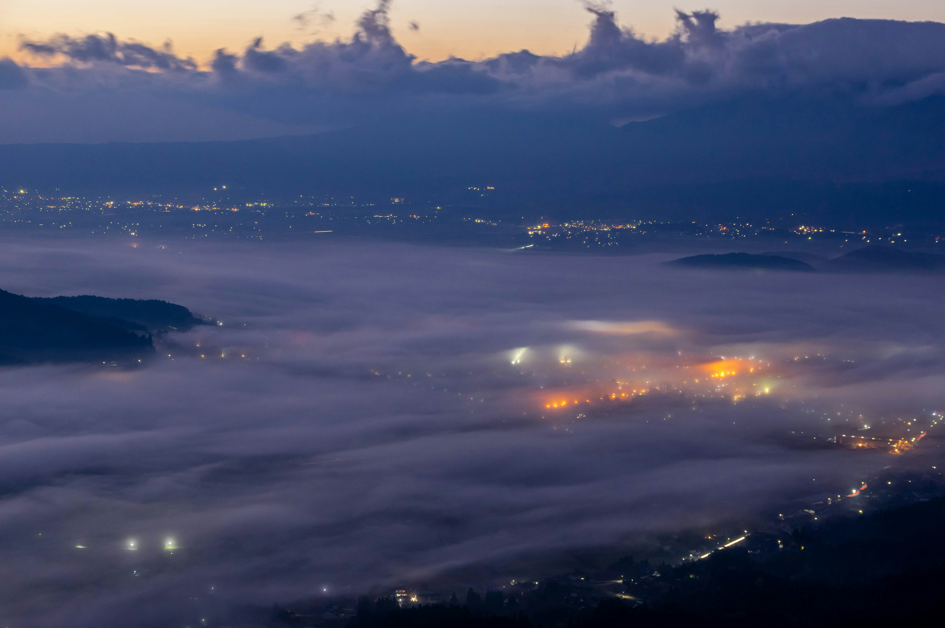 Paesaggio nebbioso al crepuscolo con luci scintillanti