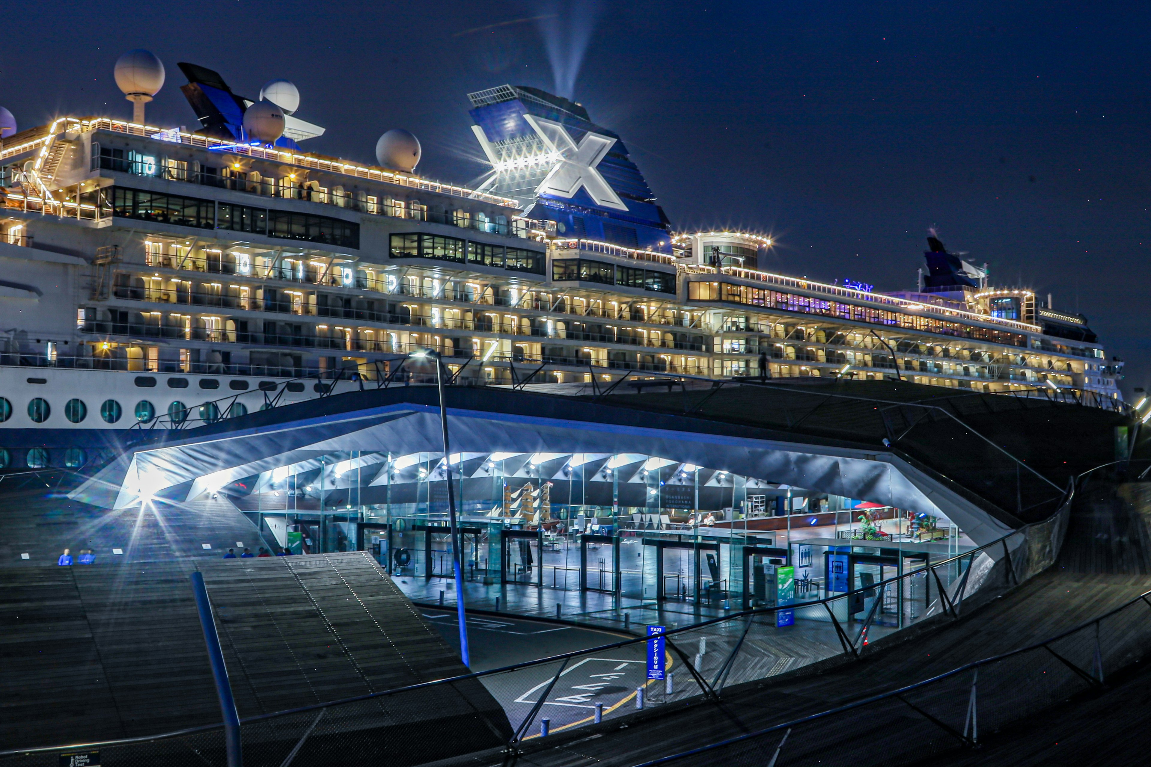 Barco de crucero de lujo atracado de noche con una terminal moderna cercana