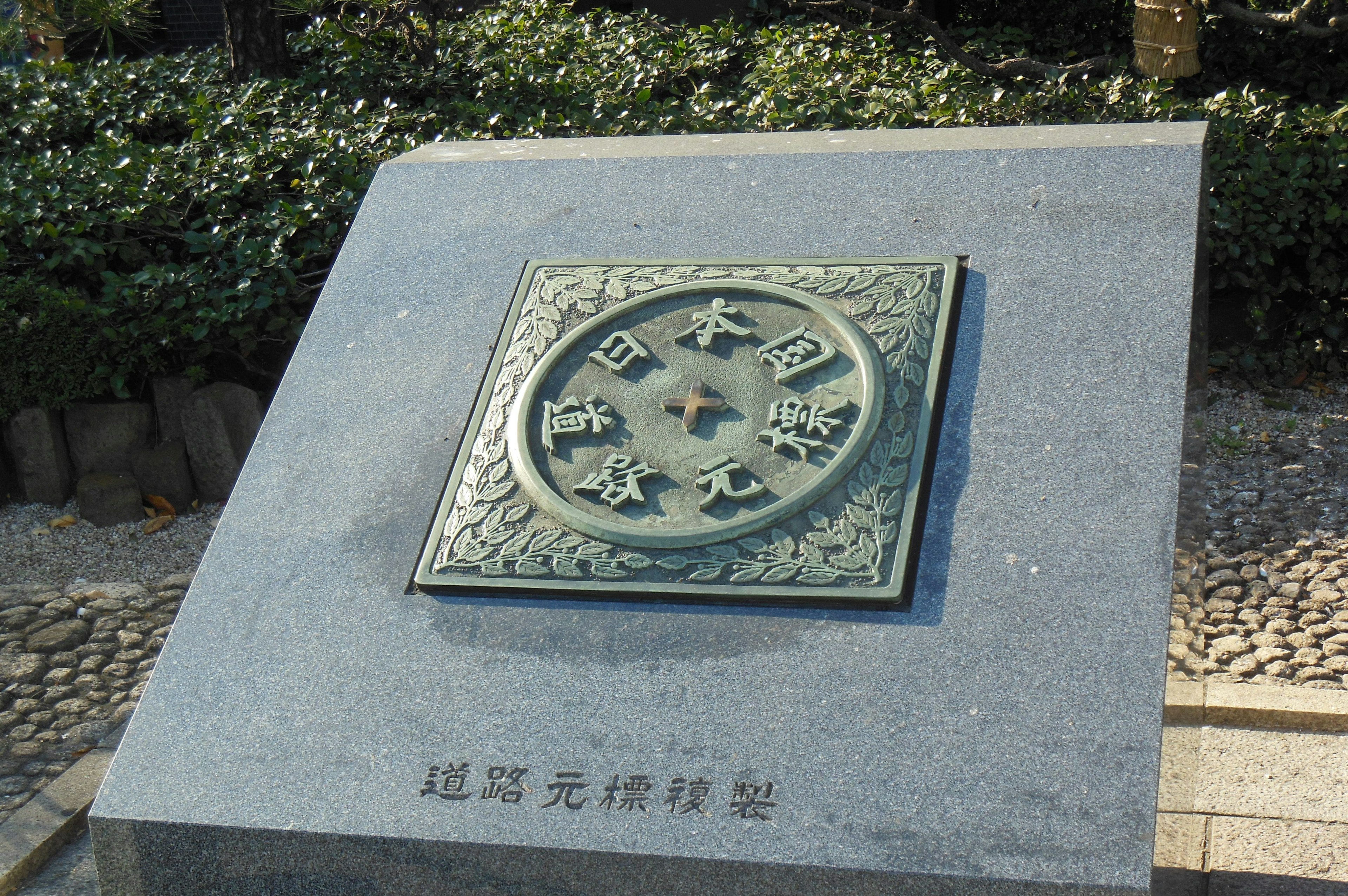 Une plaque circulaire en bronze traditionnel japonais exposée sur une base en pierre