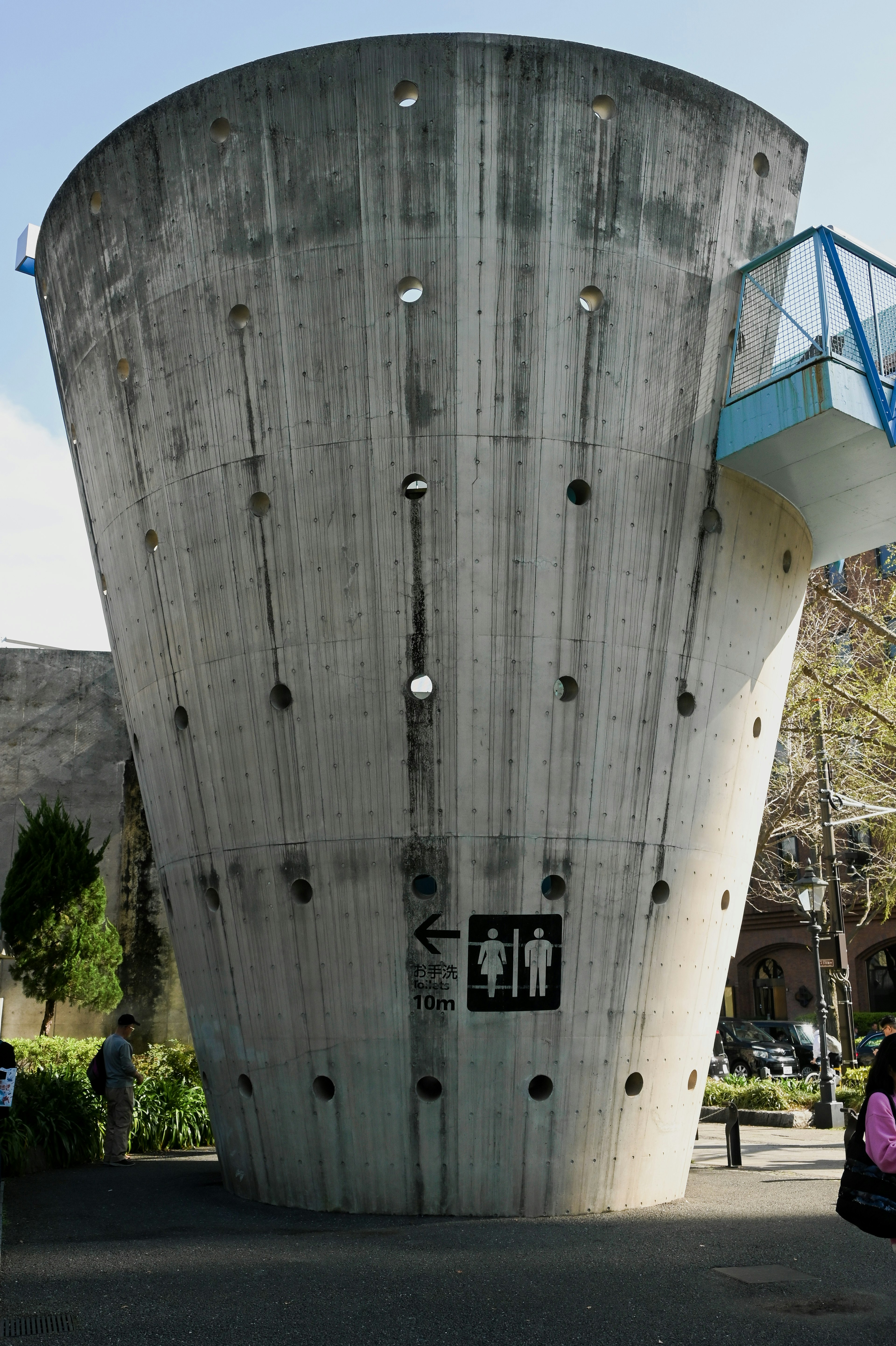 Unique concrete toilet building with conical design and blue railing