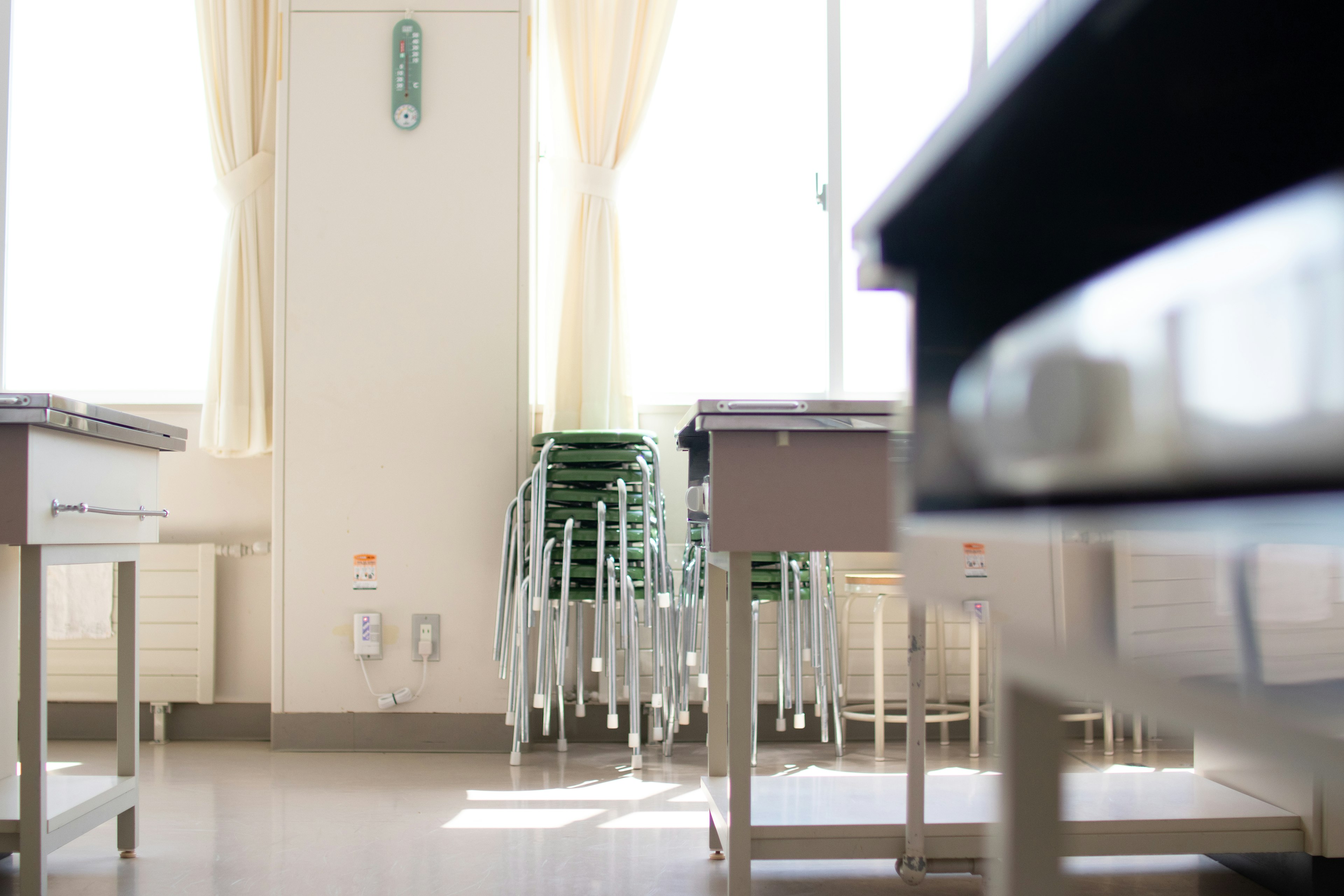 Helles Klassenraum-Interieur mit natürlichem Licht, das durch das Fenster kommt, Tische und Stühle ordentlich angeordnet