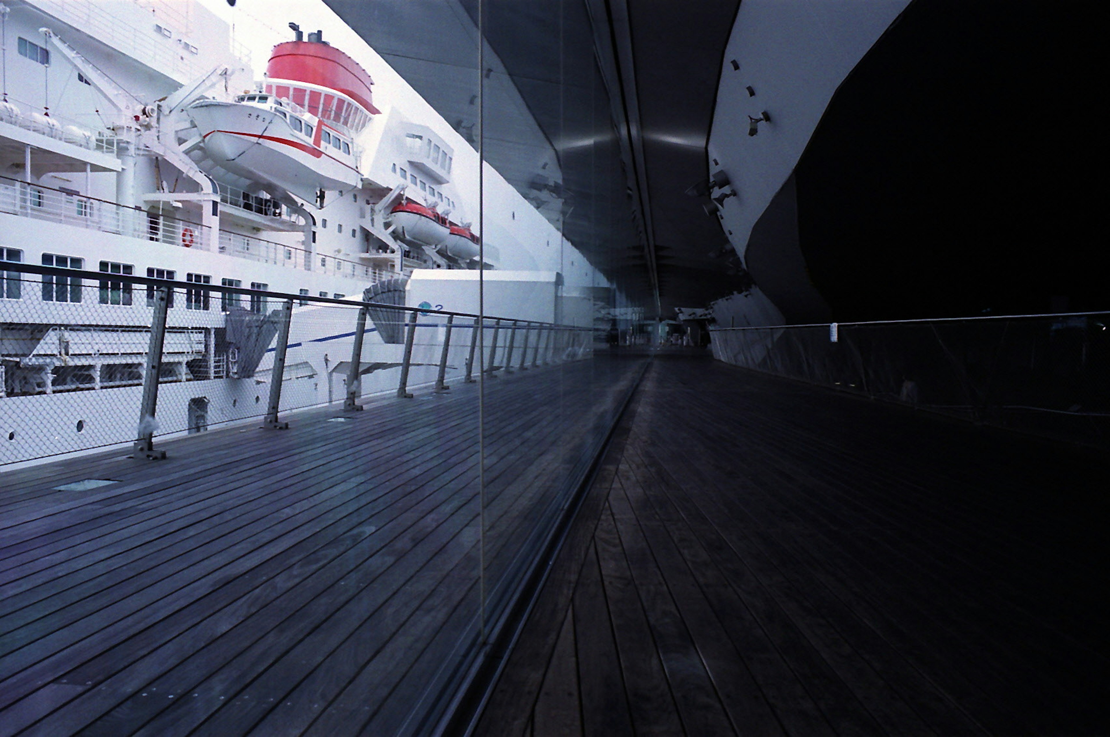 Vista laterale di una nave da crociera con riflessi di vetro e ponte in legno