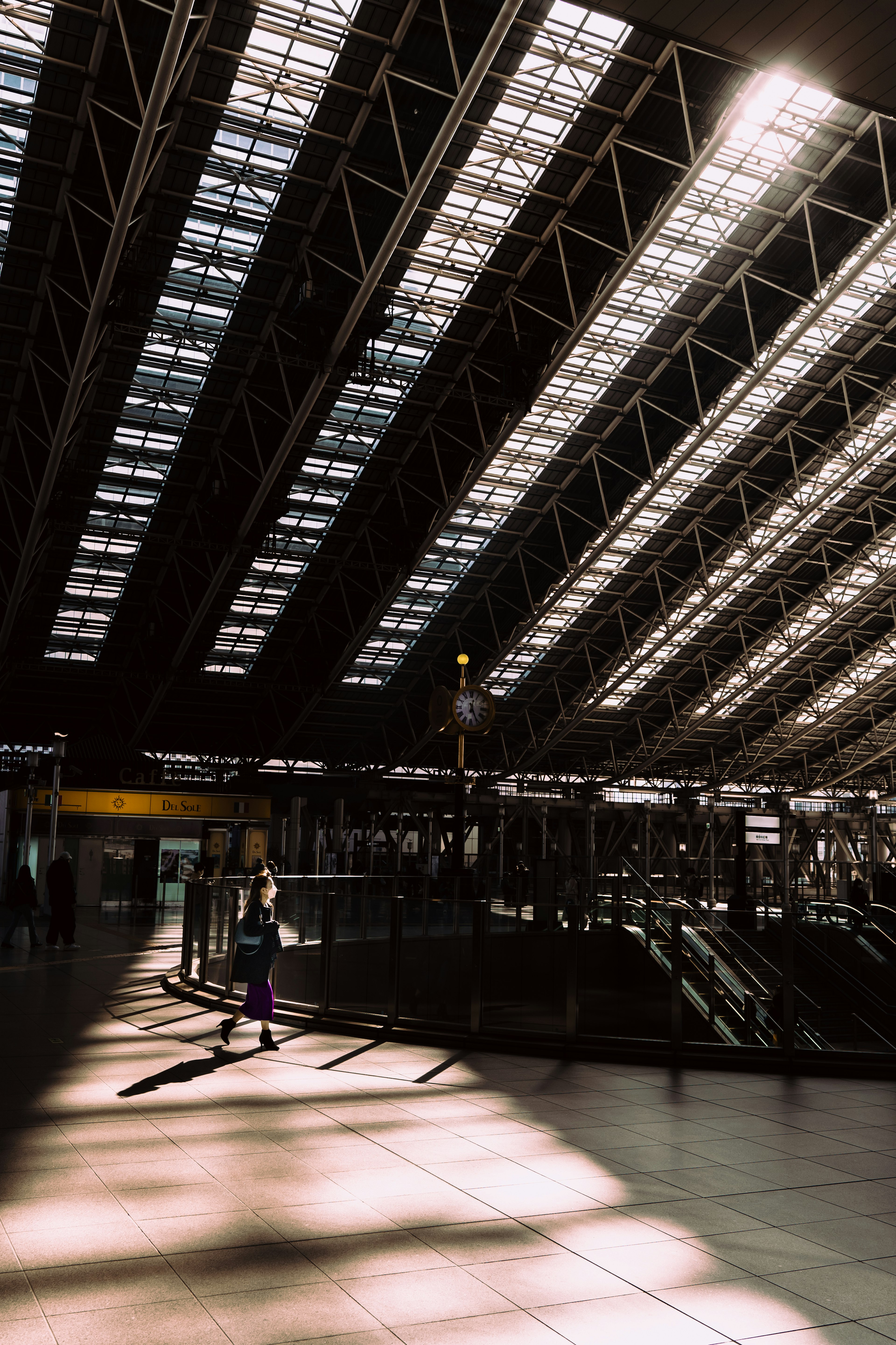 Modern train station interior with sunlight streaming through skylights shadows on the floor