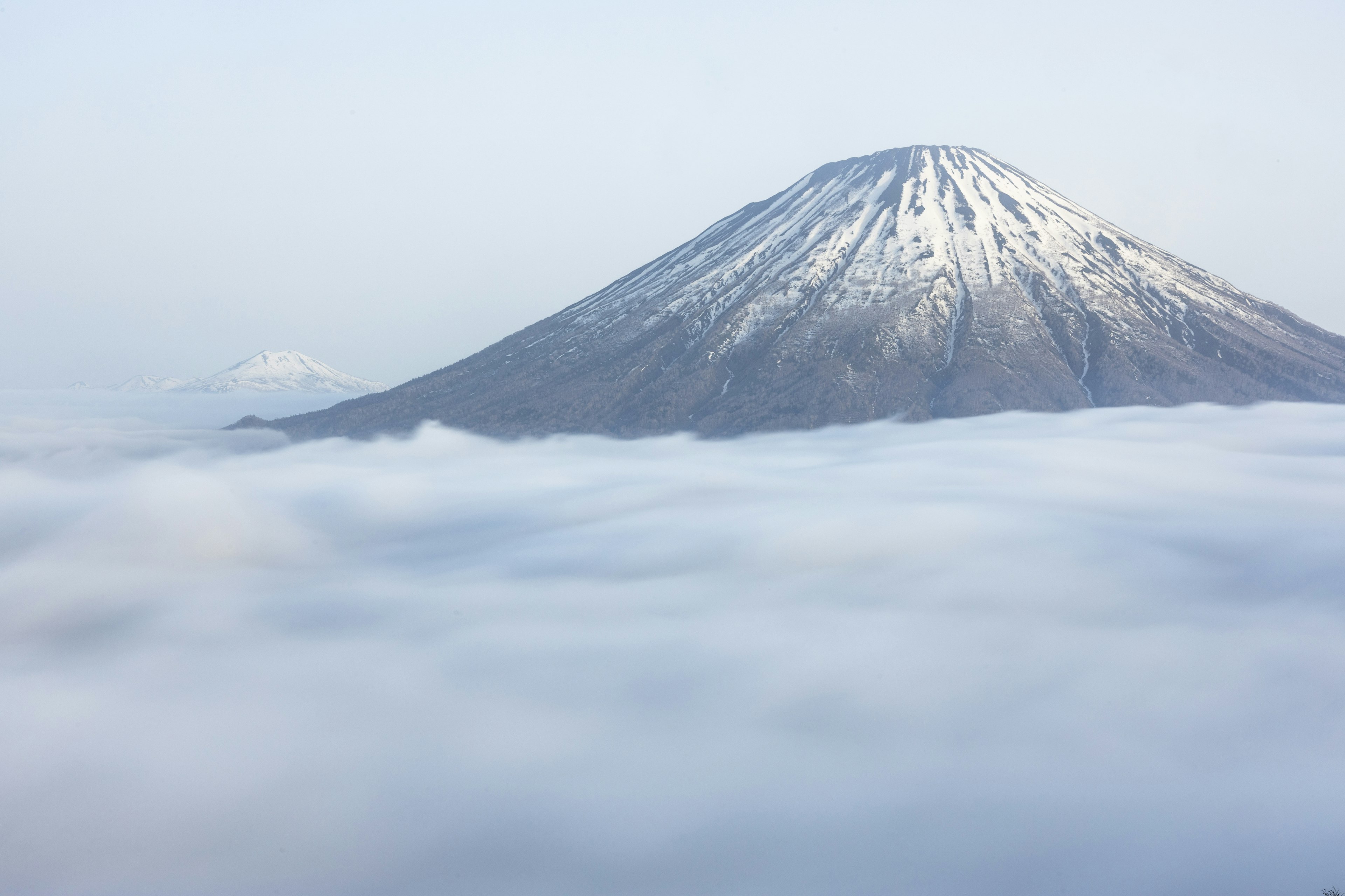 雪をかぶった山が雲の上にそびえる風景