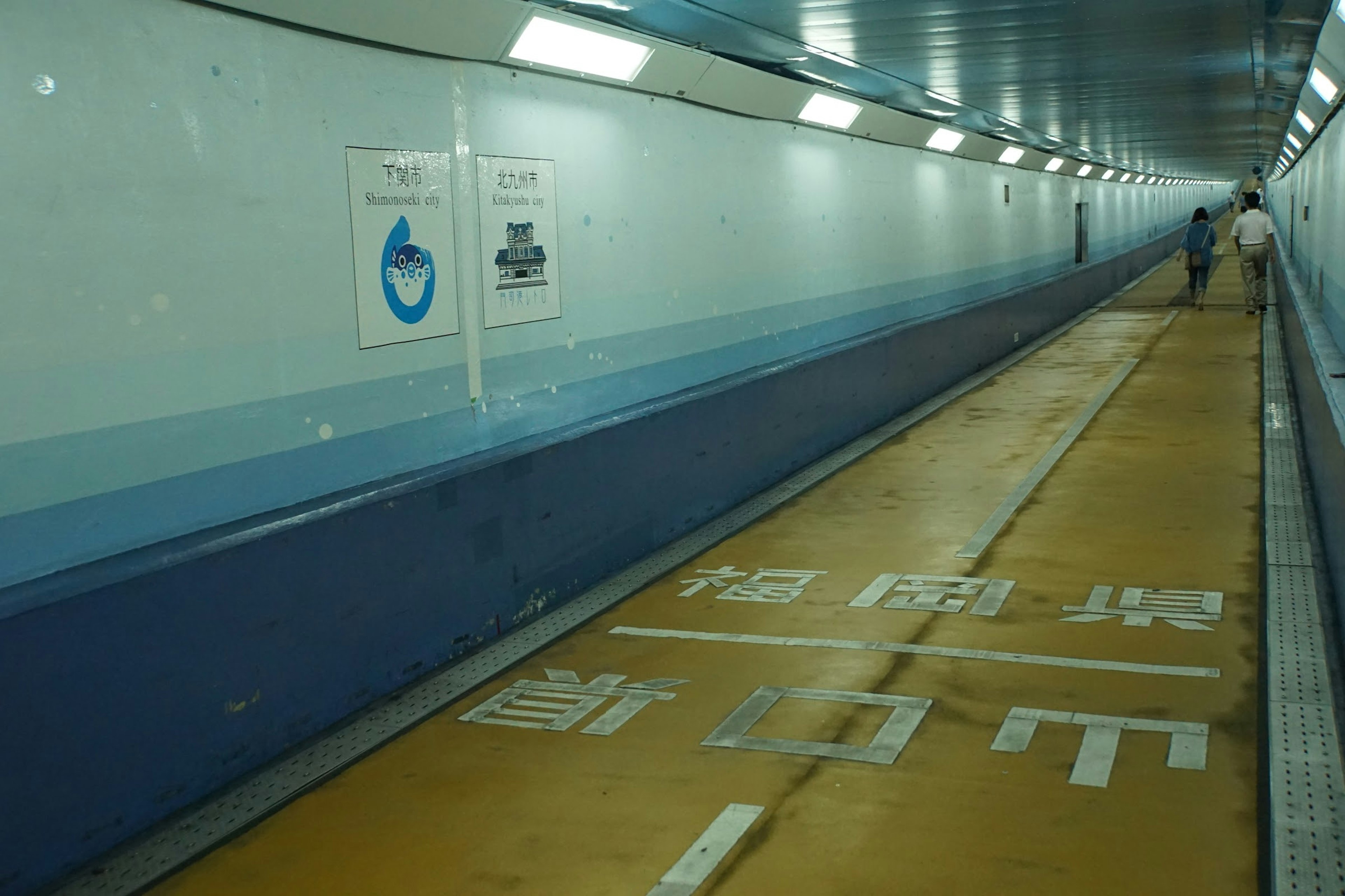 Intérieur d'un tunnel piétonnier avec des murs bleus et un sol jaune