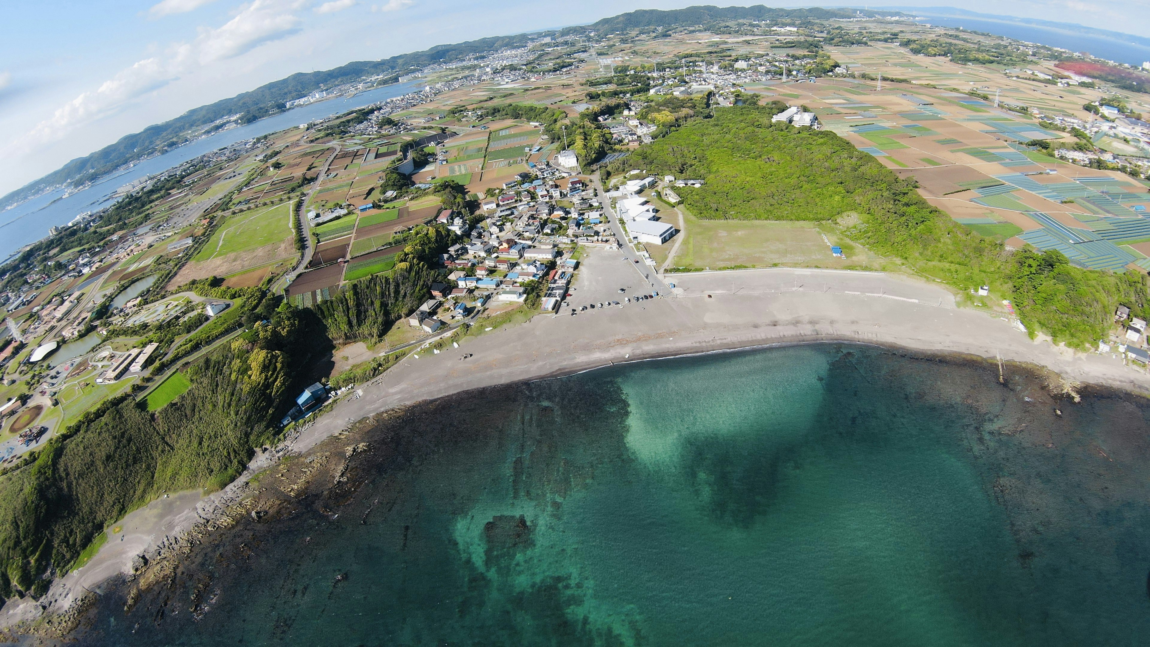 Vista aérea de una zona costera con una aldea y un paisaje verde