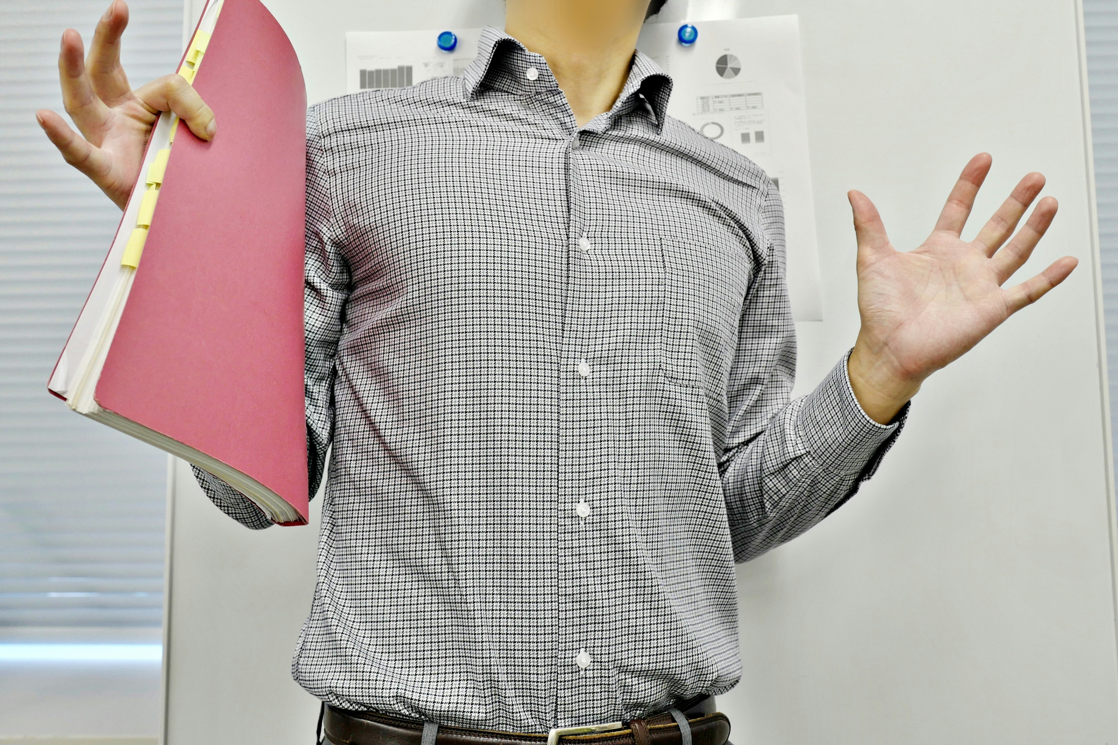 Un hombre con camisa a cuadros levantando las manos mientras sostiene un archivo rosa