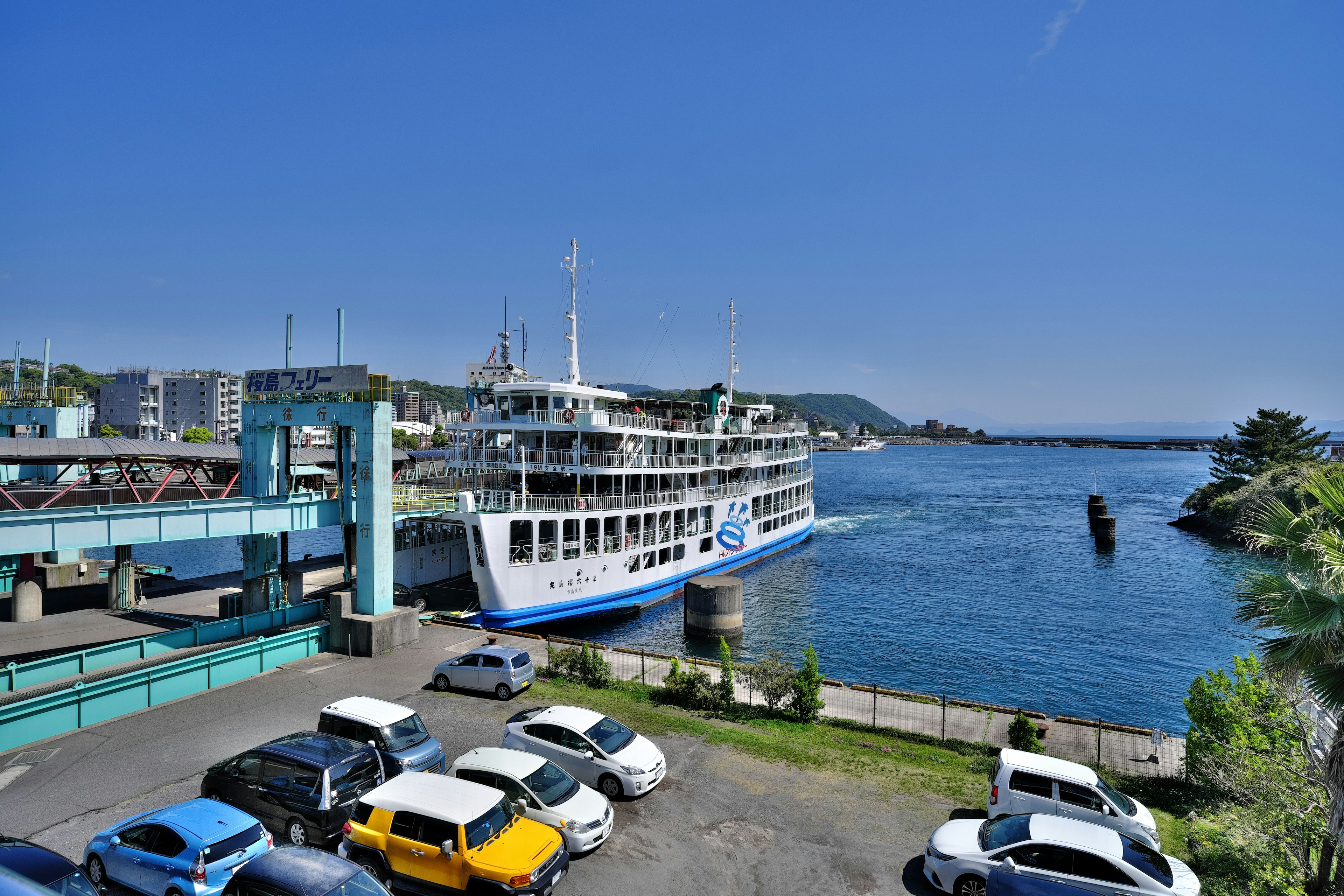 ทิวทัศน์ท่าเรือที่สวยงามพร้อมเรือเฟอร์รี่สีขาวขนาดใหญ่และรถที่จอดอยู่