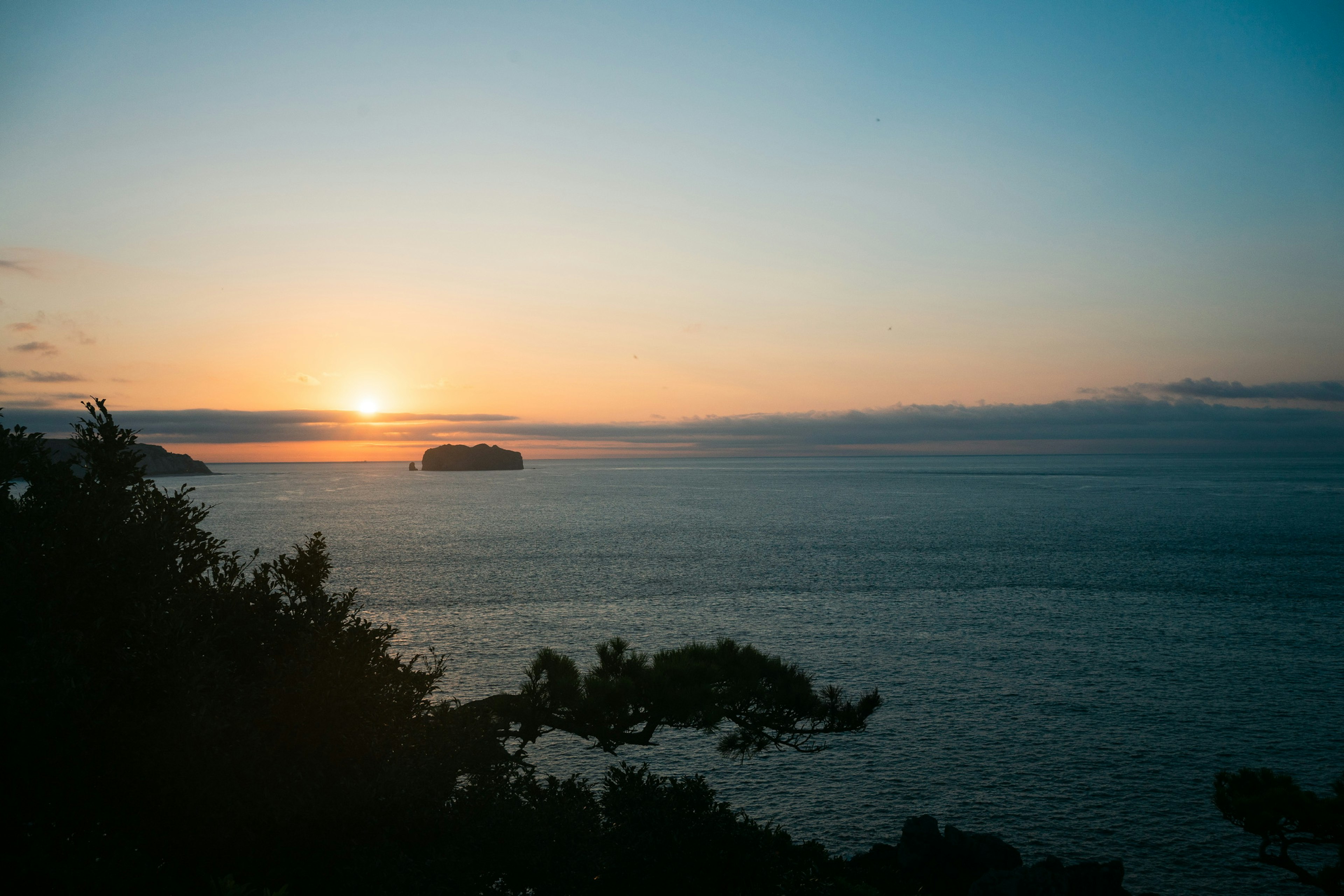 青い海と夕日が沈む風景 近くの島が見える