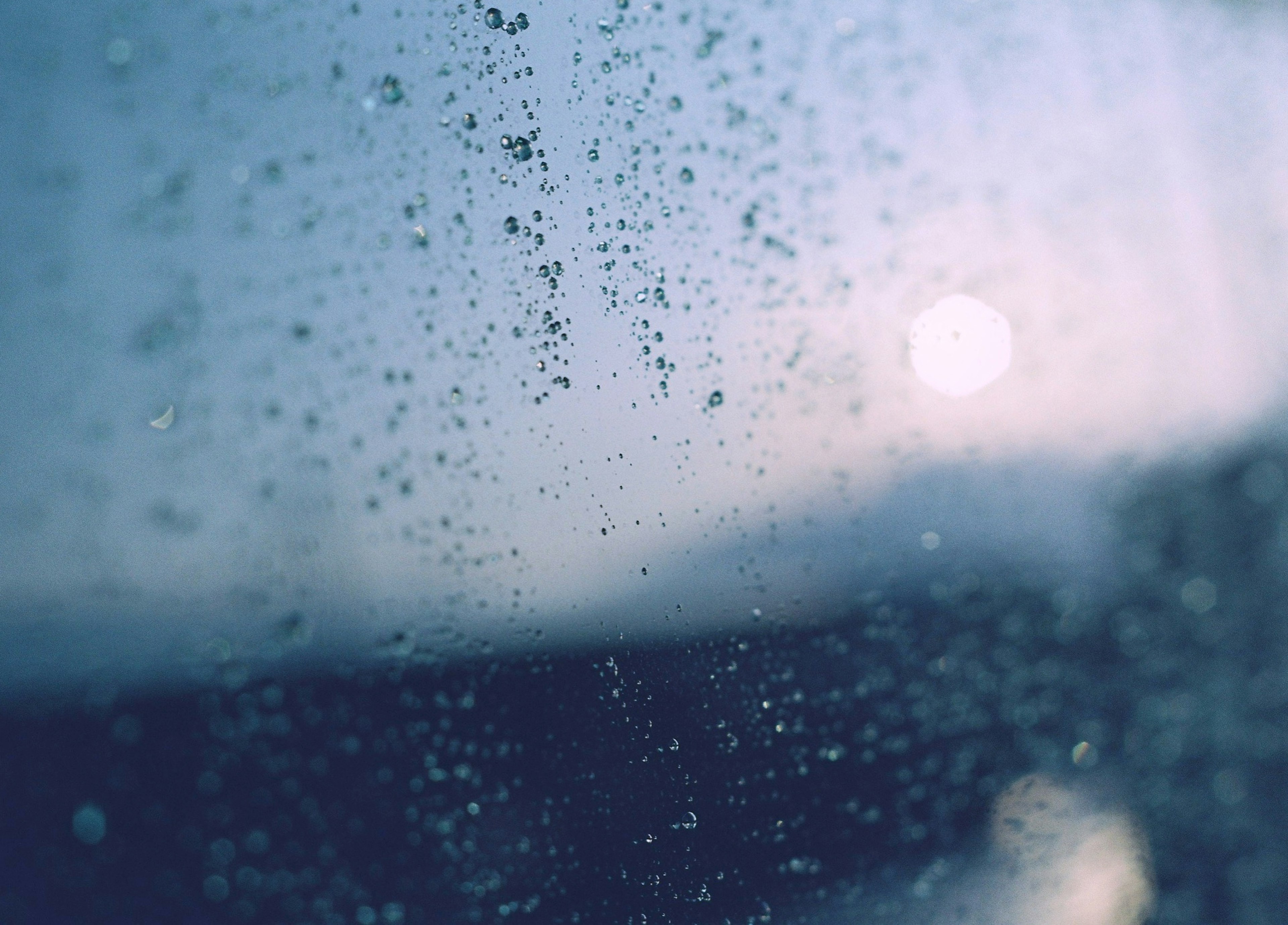 Gouttes de pluie sur une fenêtre embuée avec un arrière-plan bleu doux