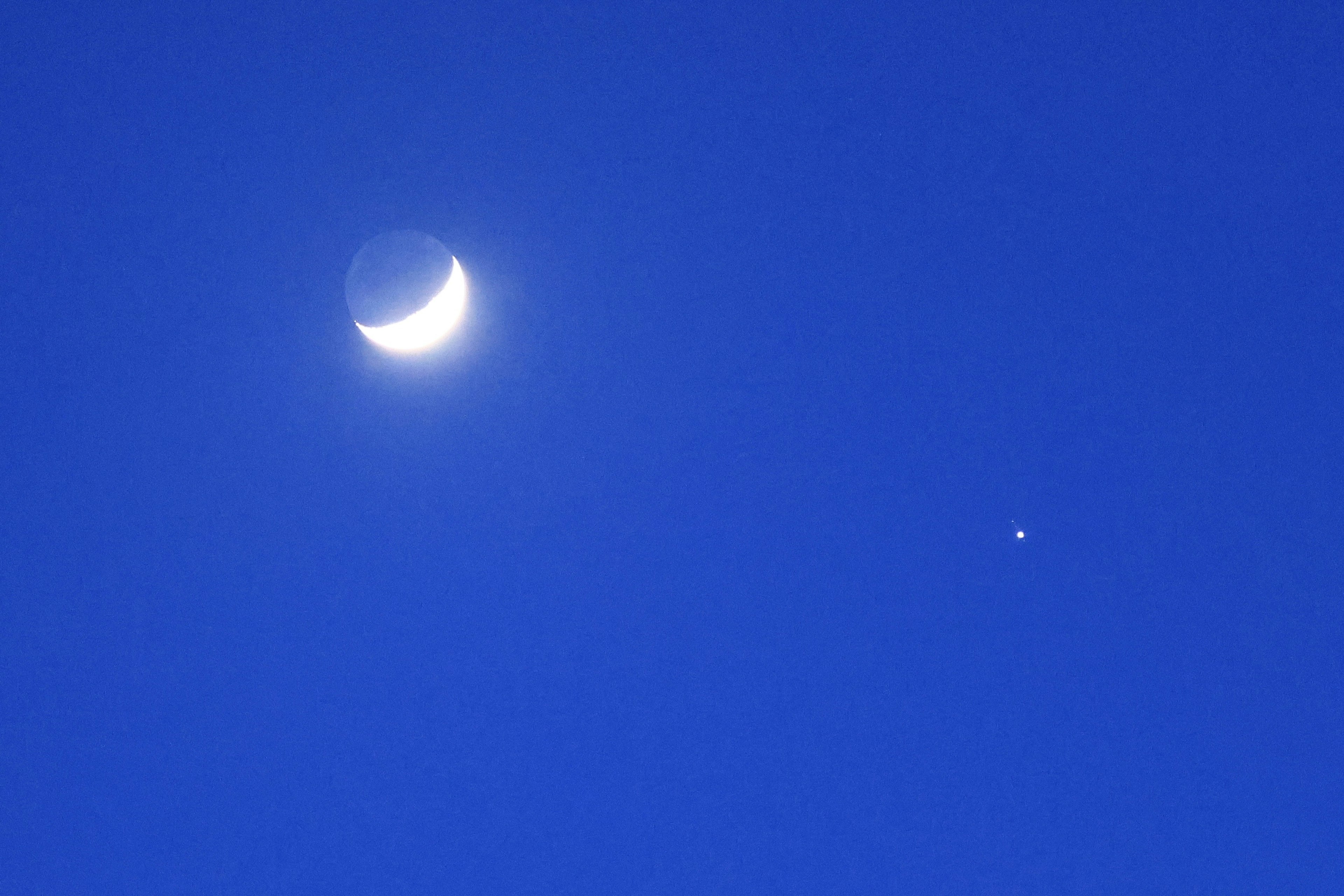 Crescent moon and small star in a blue sky