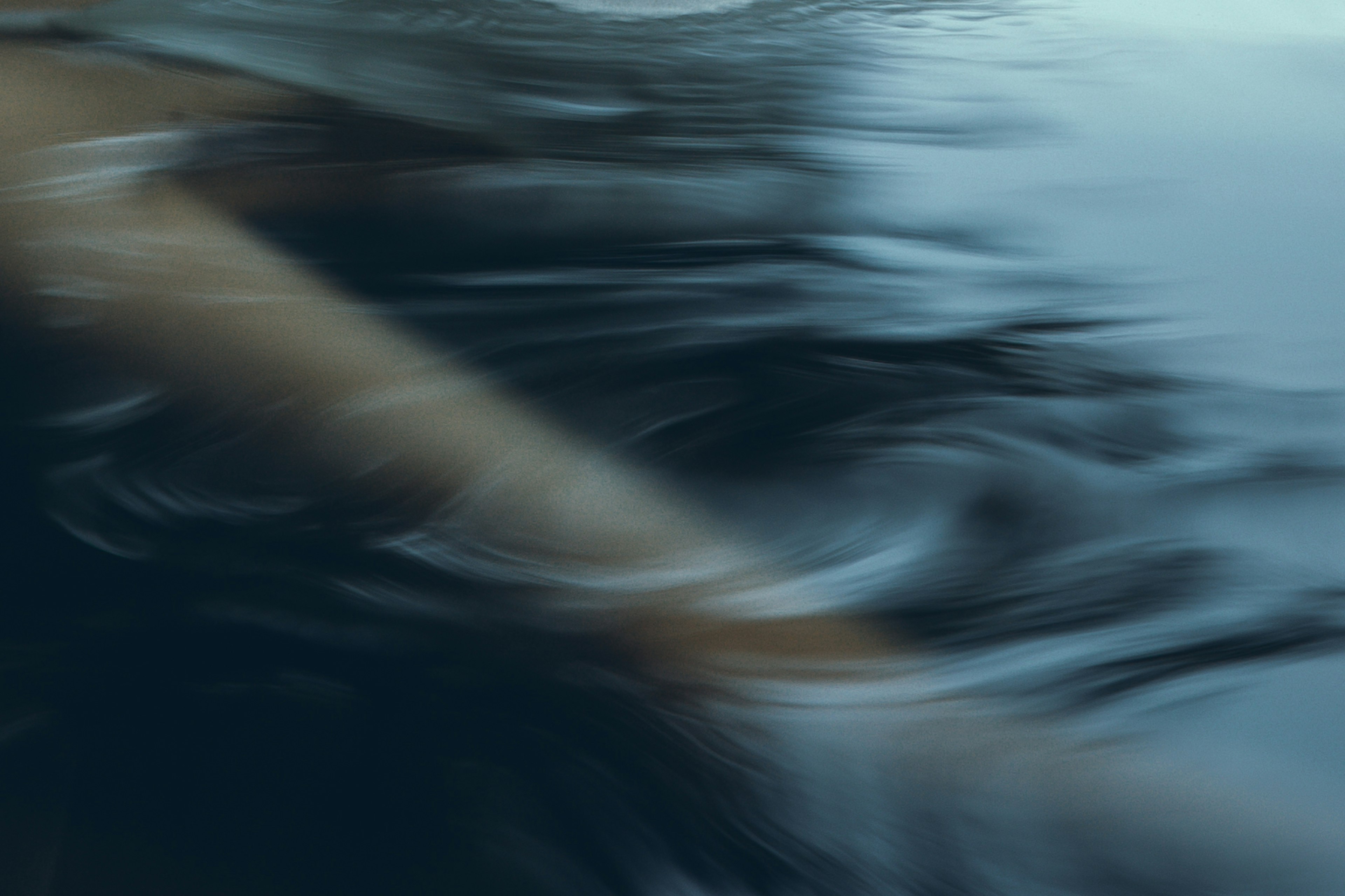 Blurred arm movement creating ripples on the water surface