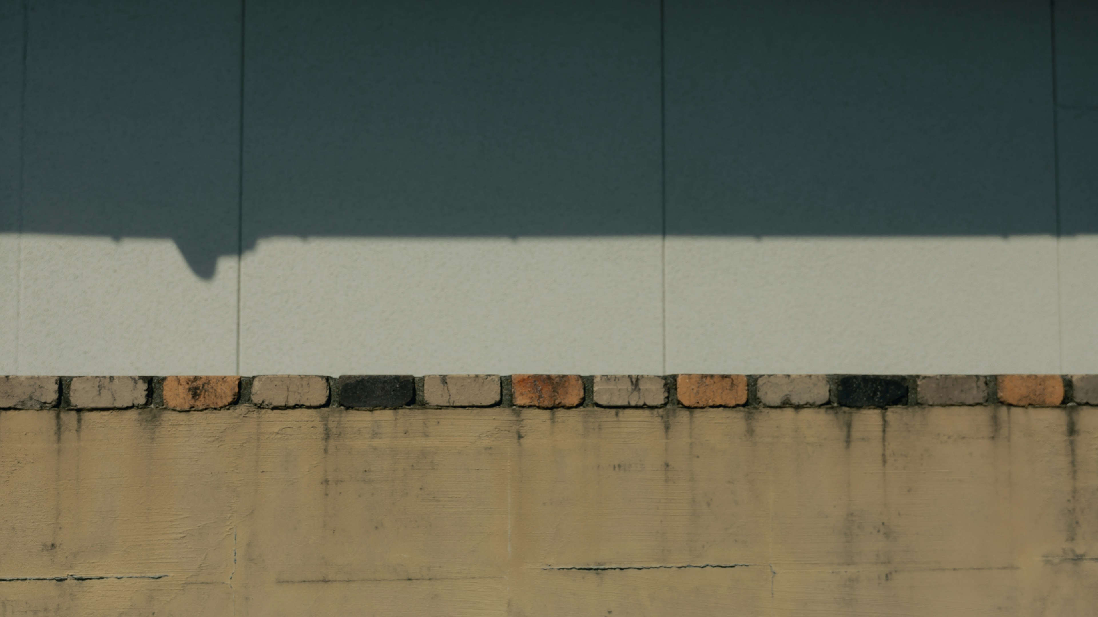 Structure avec un mur bleu et une bande blanche avec une fondation en briques en bas