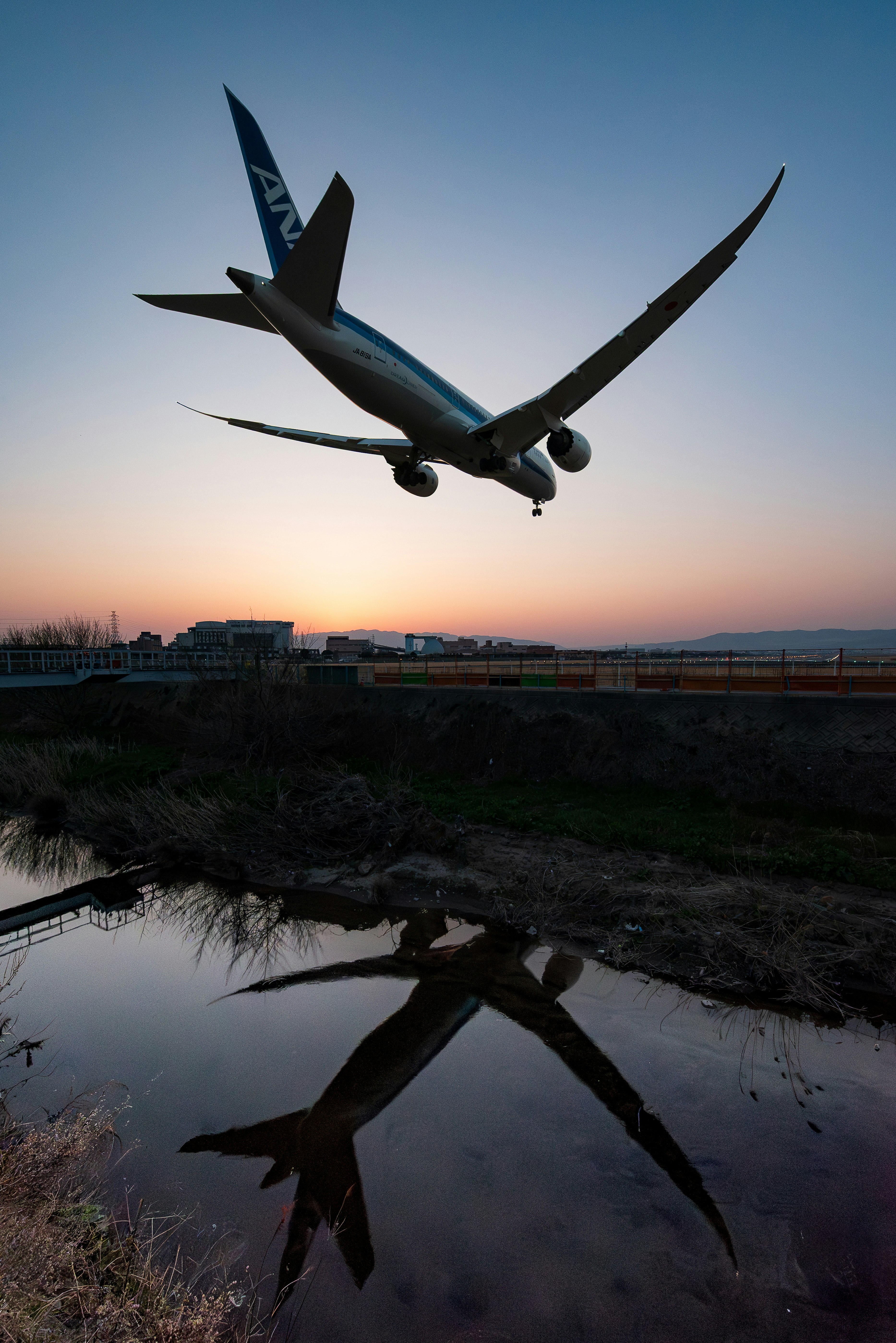 Airplane flying over a river at sunset