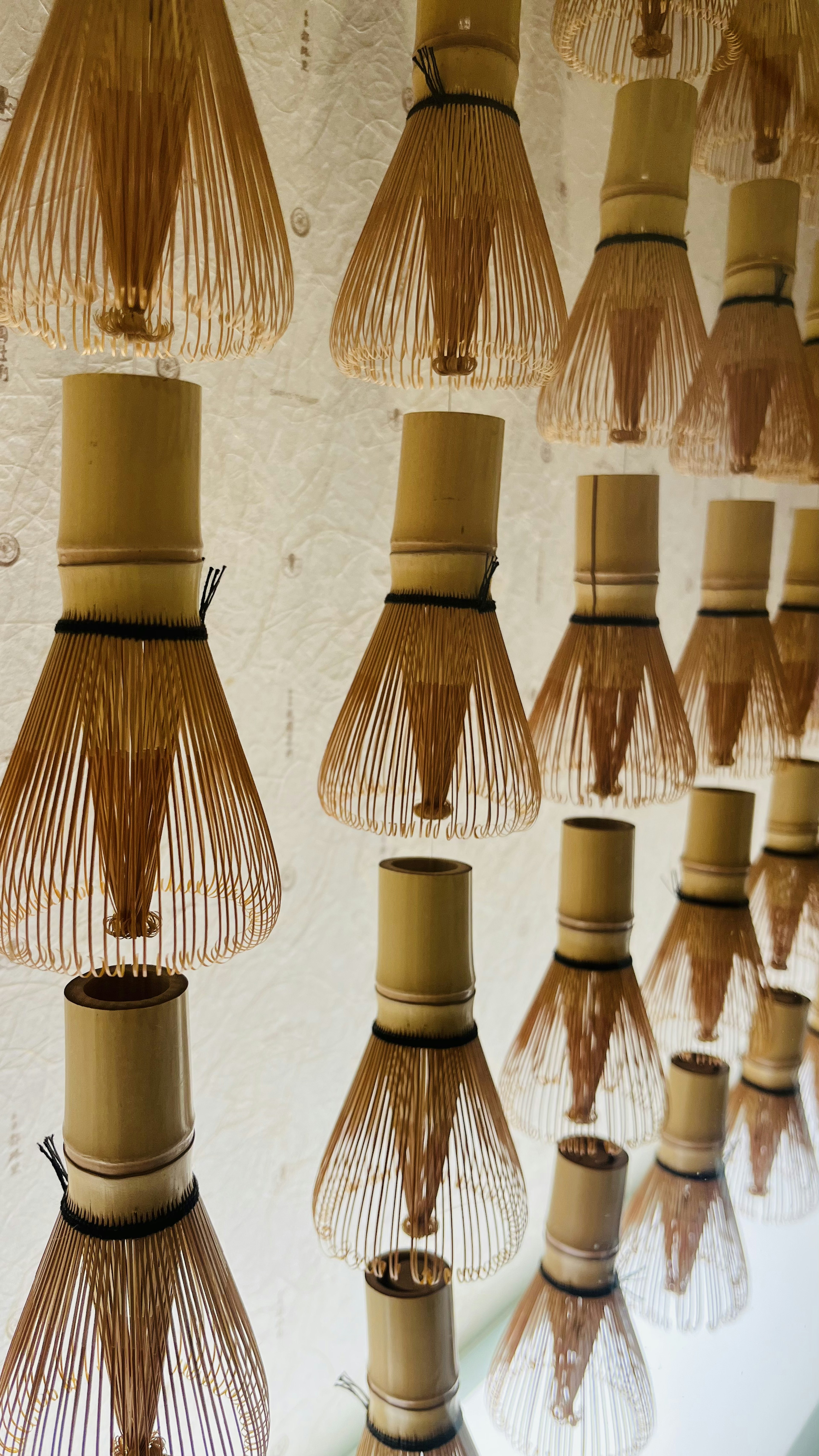 Art installation of tea whisks hanging on a wall bamboo tea whisks arranged in a pattern