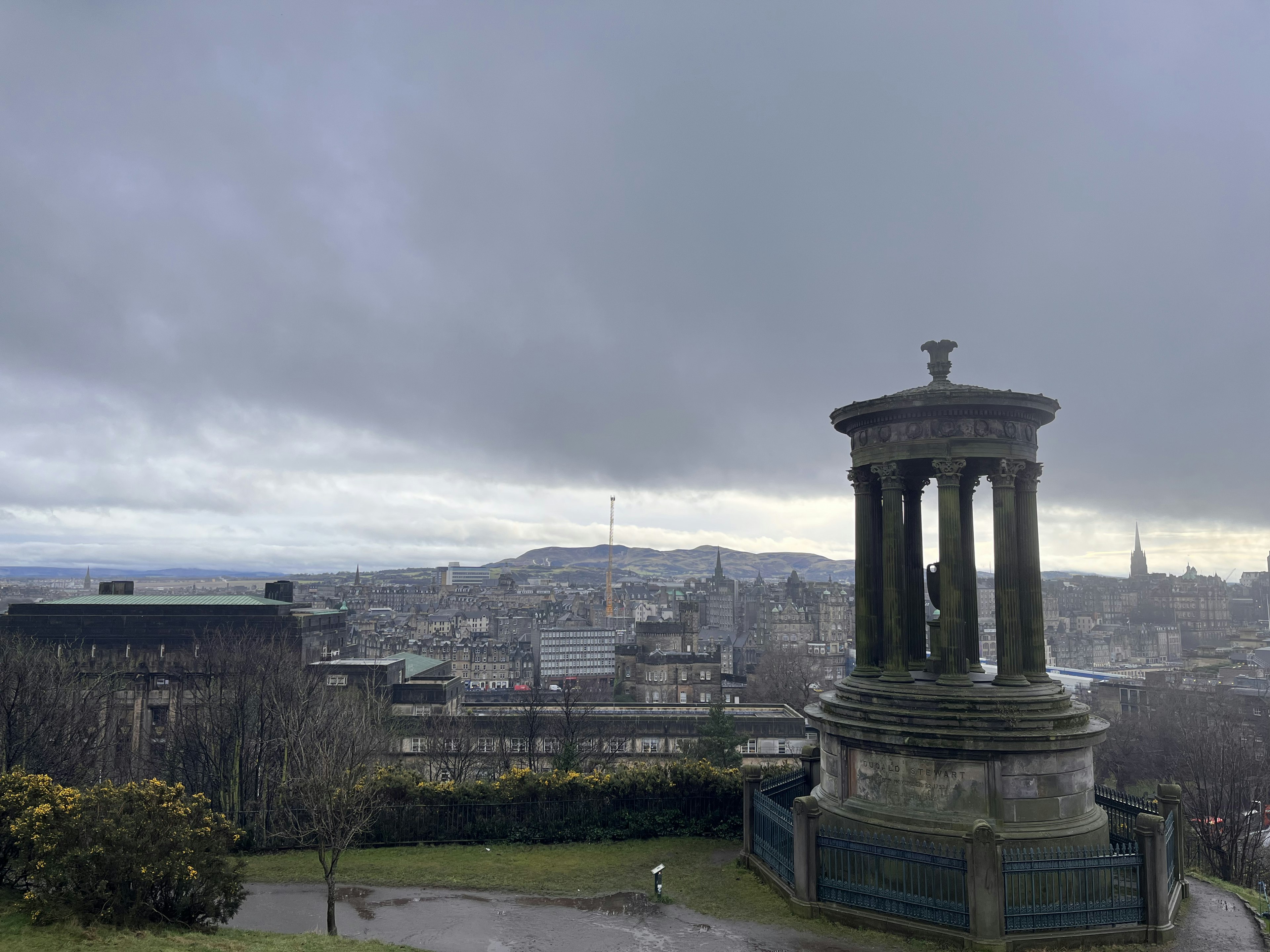 Aussicht von einem Hügel über Edinburgh mit einem Denkmal und bewölktem Himmel