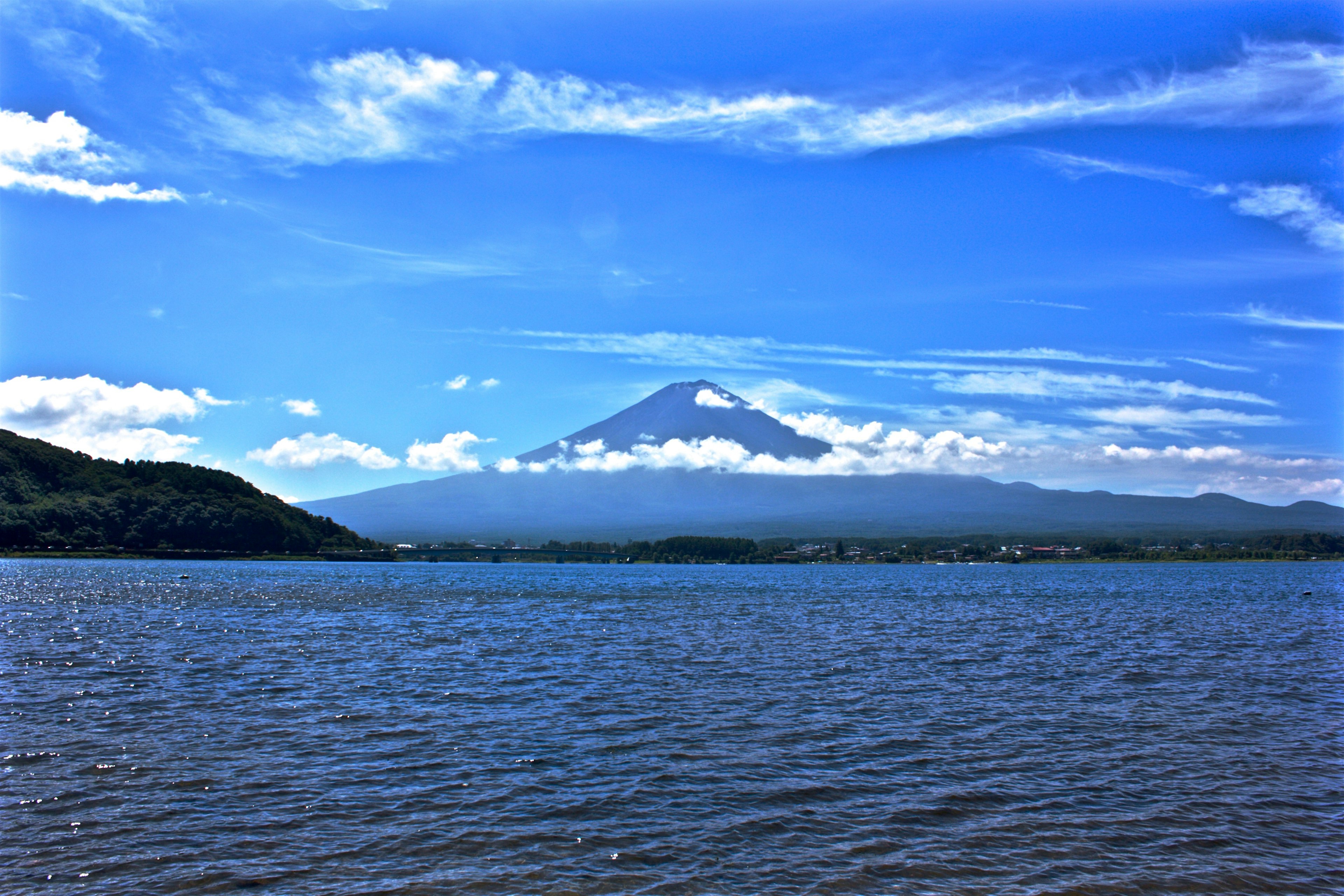 湖面上方藍天下雲霧繚繞的富士山風景