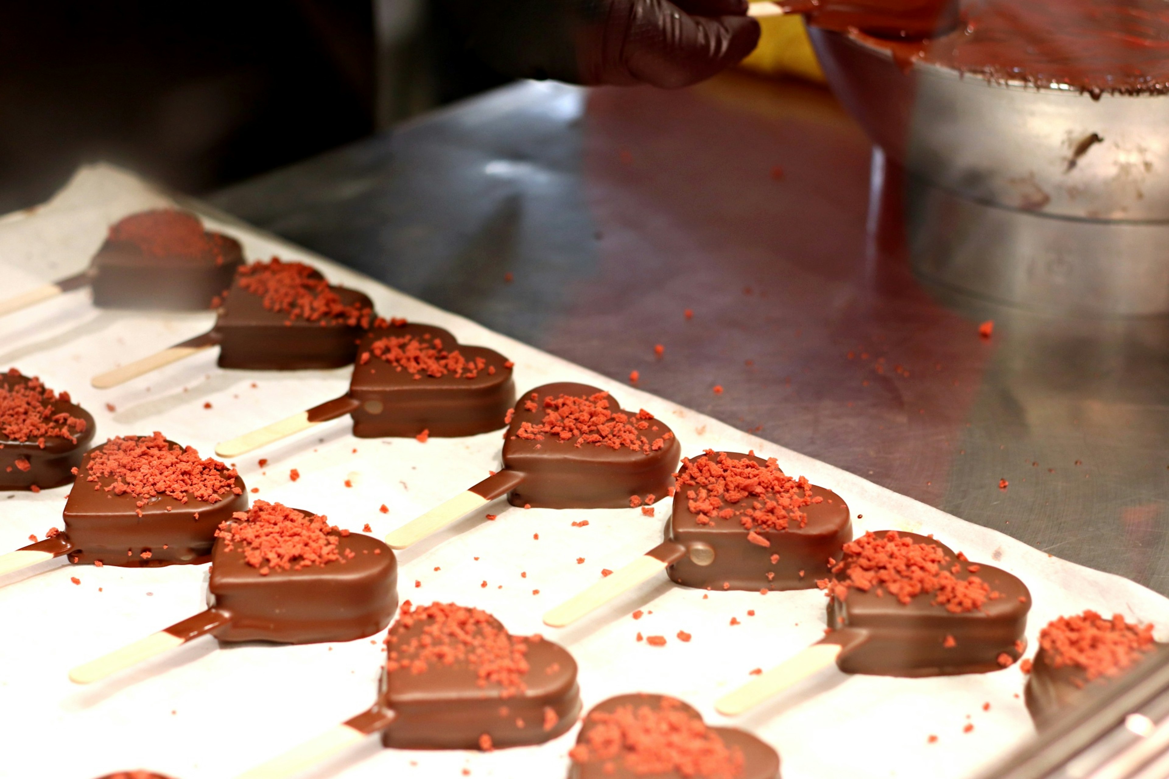 Heart-shaped chocolate ice cream pops on sticks arranged on a tray