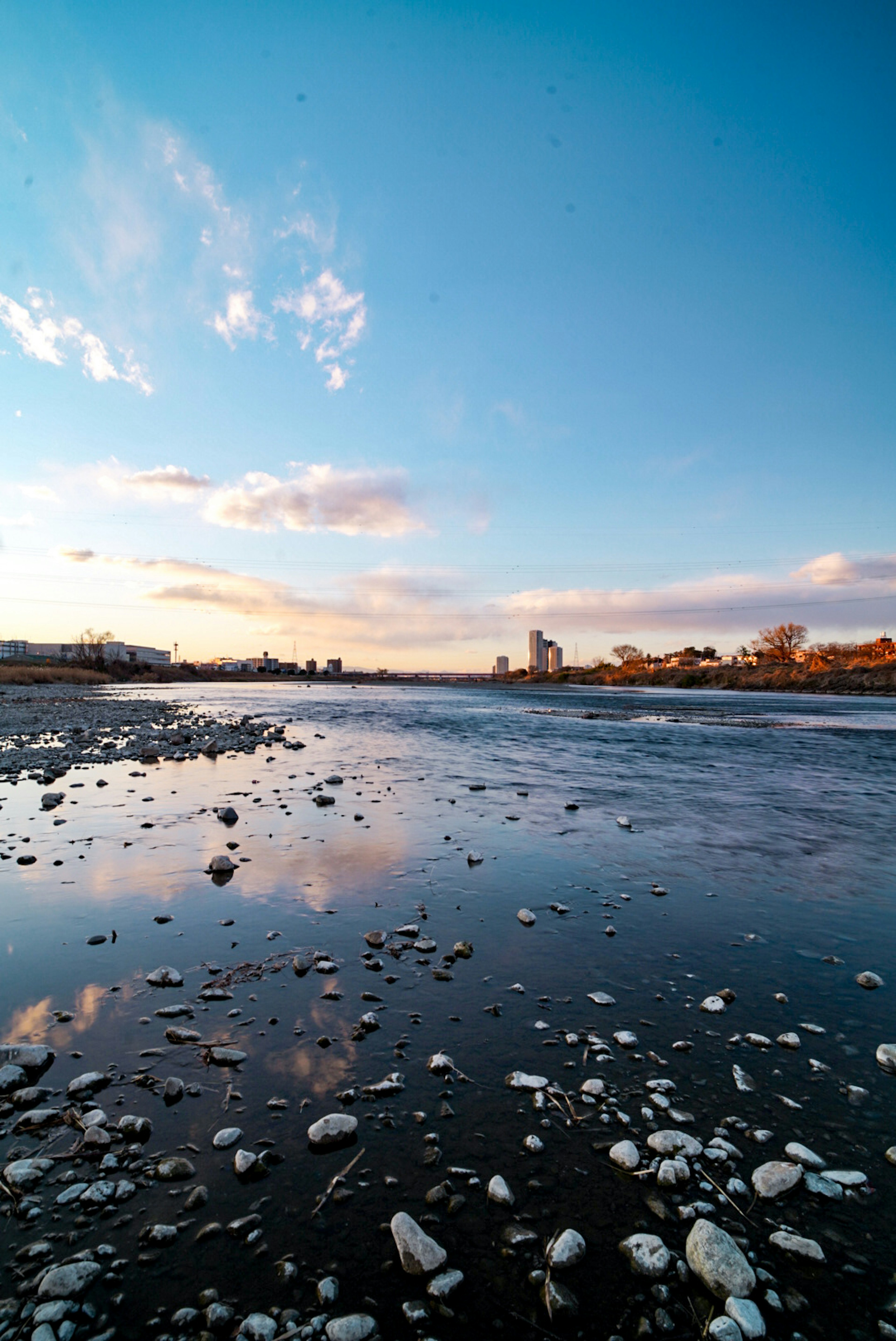 River landscape with blue sky and clouds reflecting on the water unique stones and pebbles