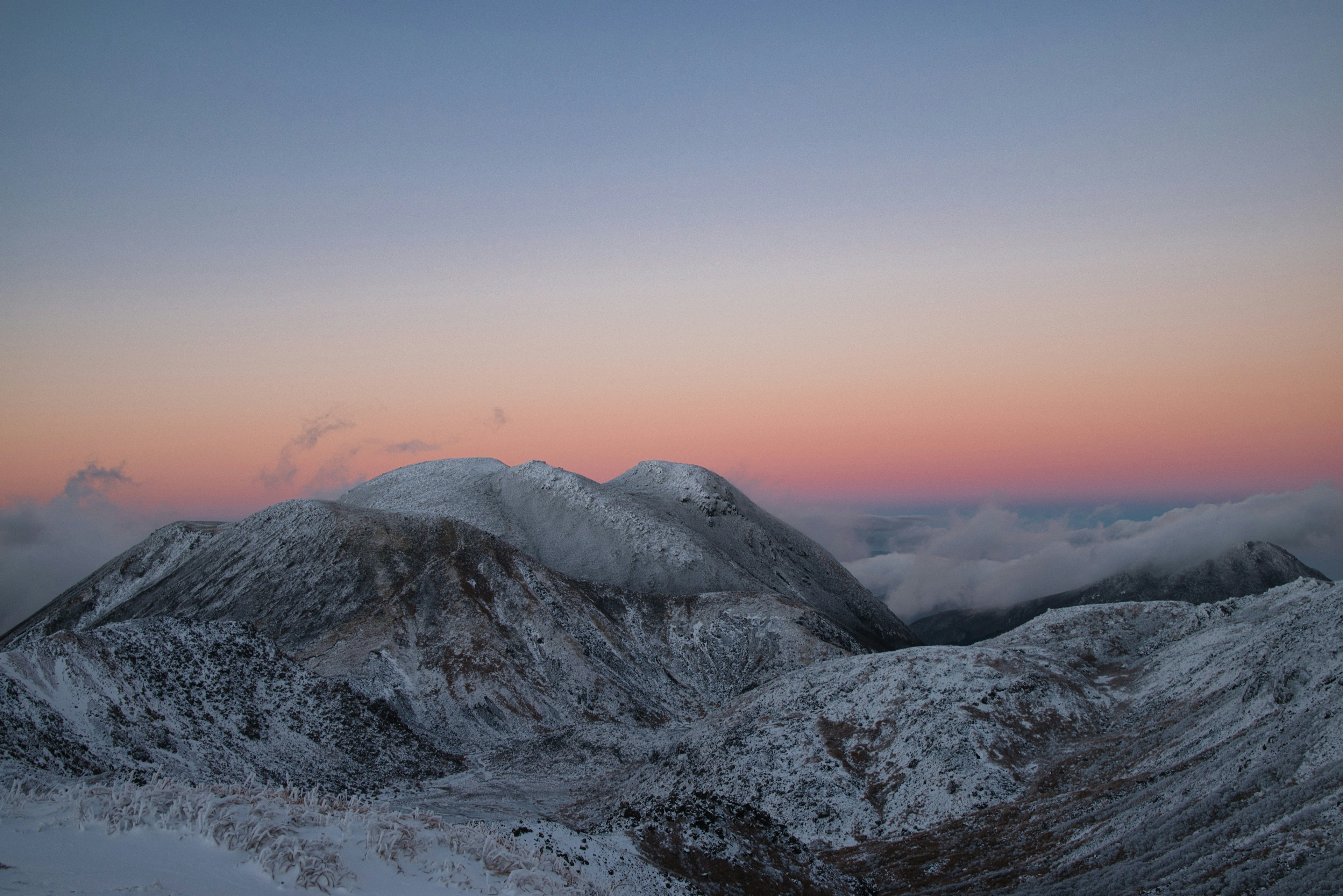 Montagne innevate sotto un cielo tenue dell'alba