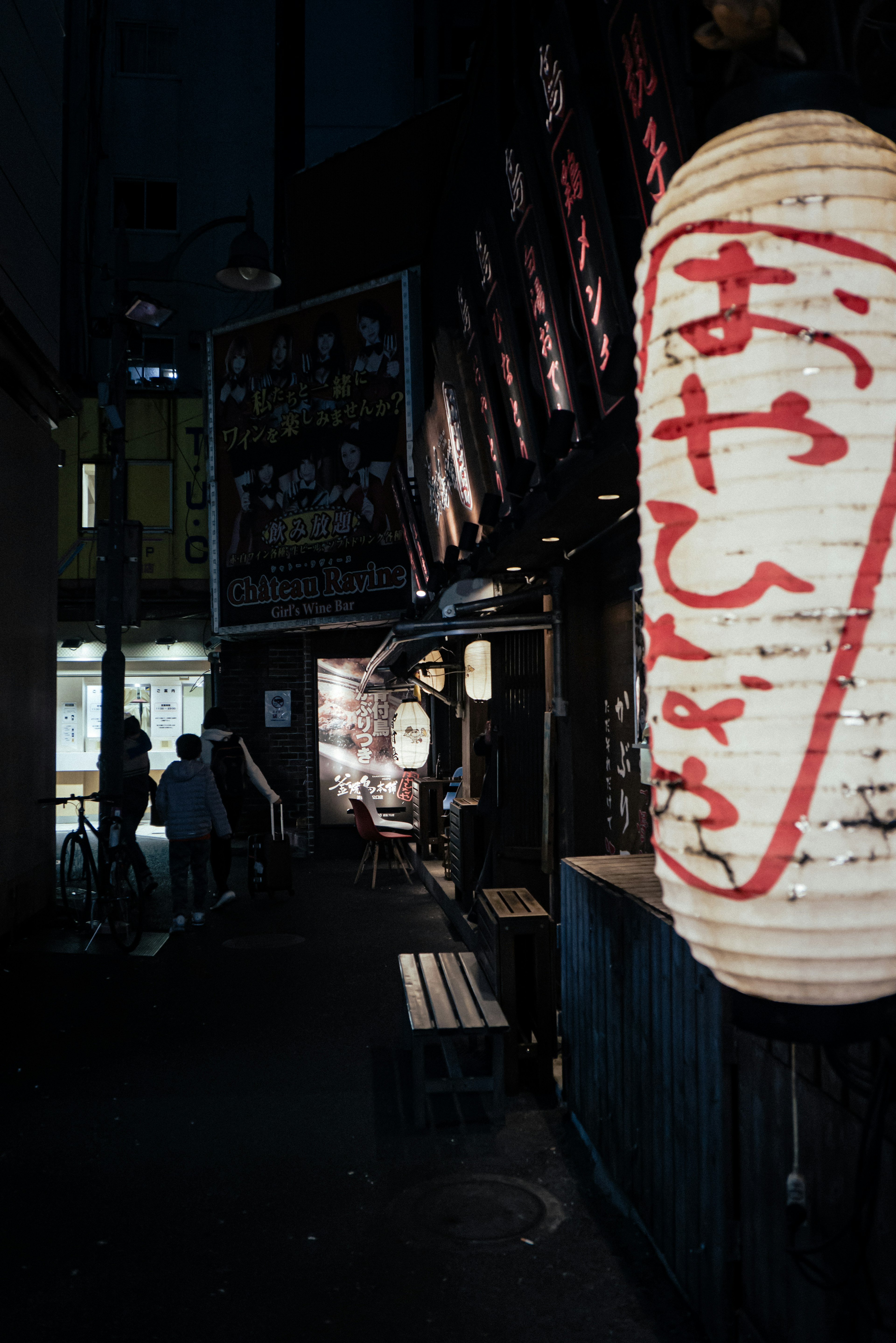 屋台の明かりがともる夜の街並みと人々のシルエット