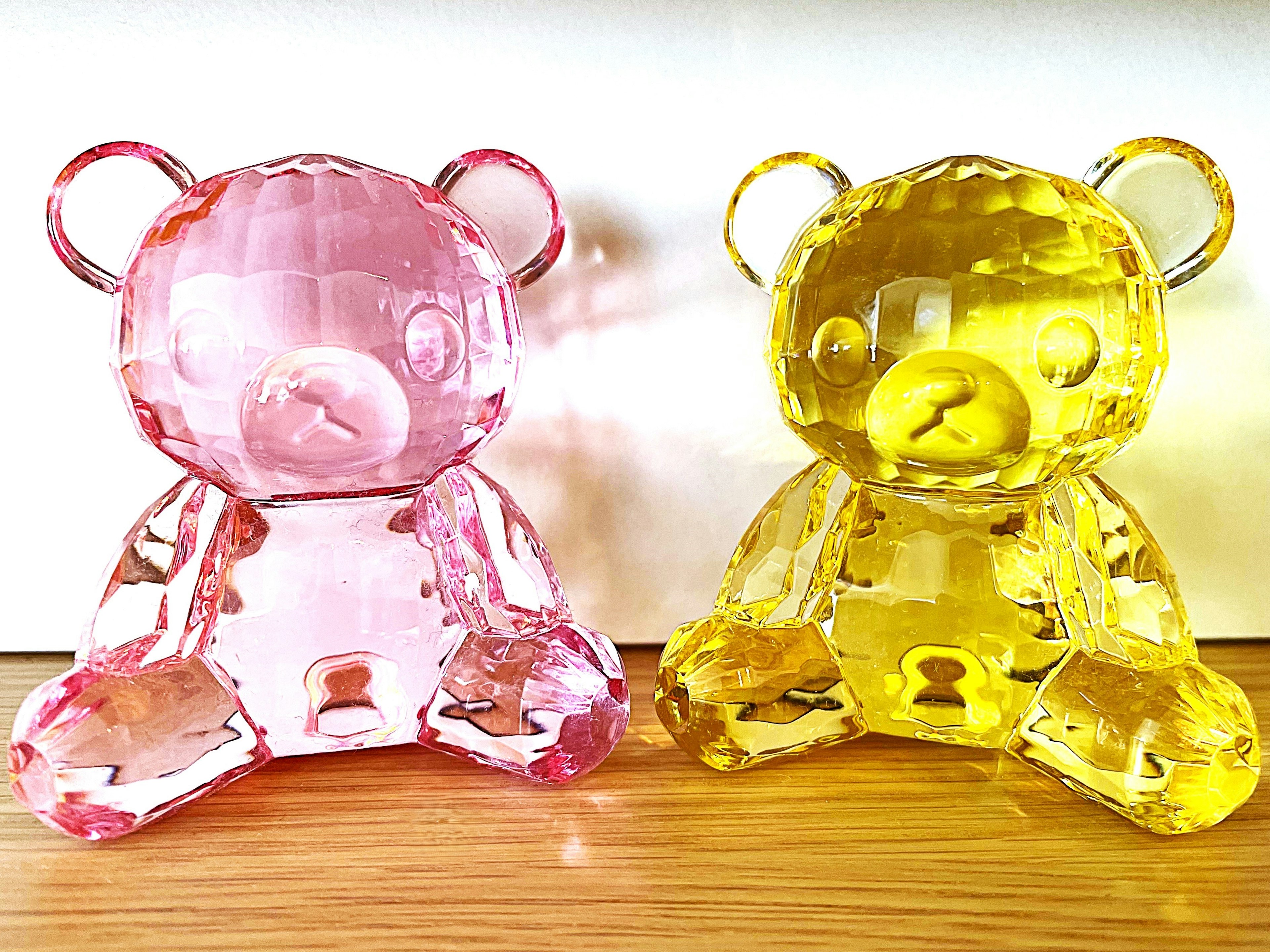 Two transparent bear figurines in pink and yellow colors sitting side by side