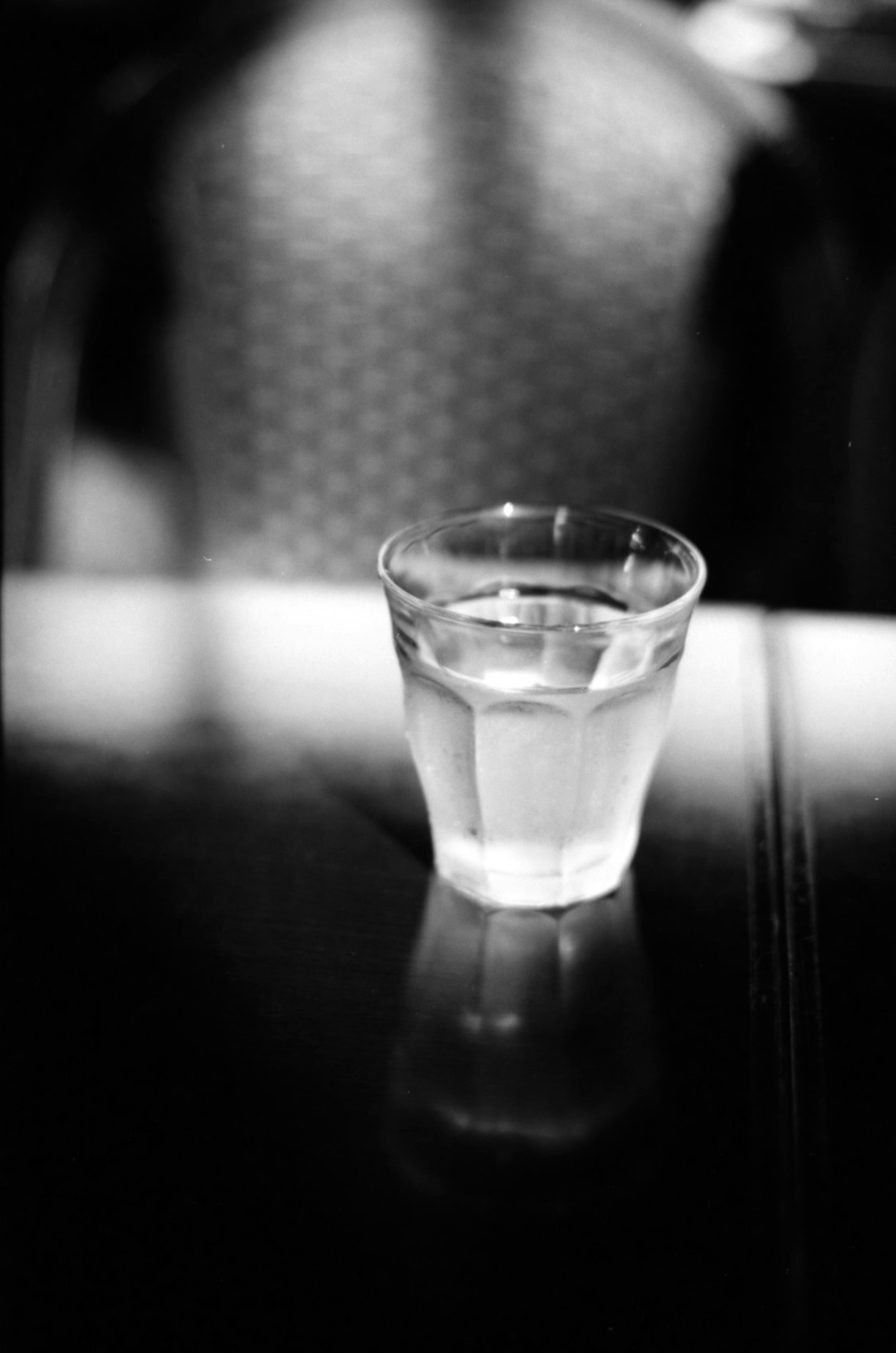 Un verre d'eau clair sur une table capturé dans une image simple en noir et blanc