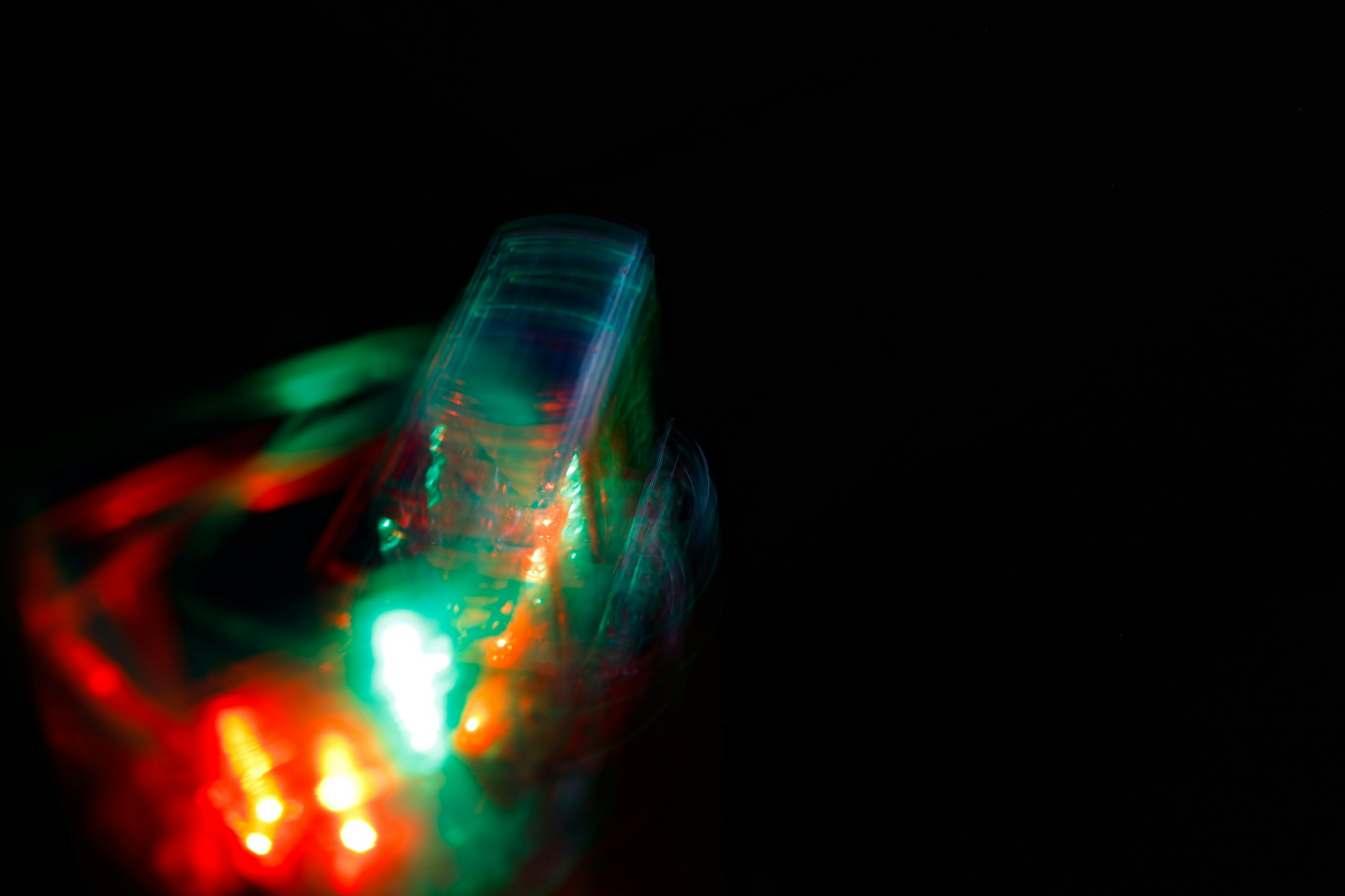 Blurred image of an object emitting red and green lights against a dark background