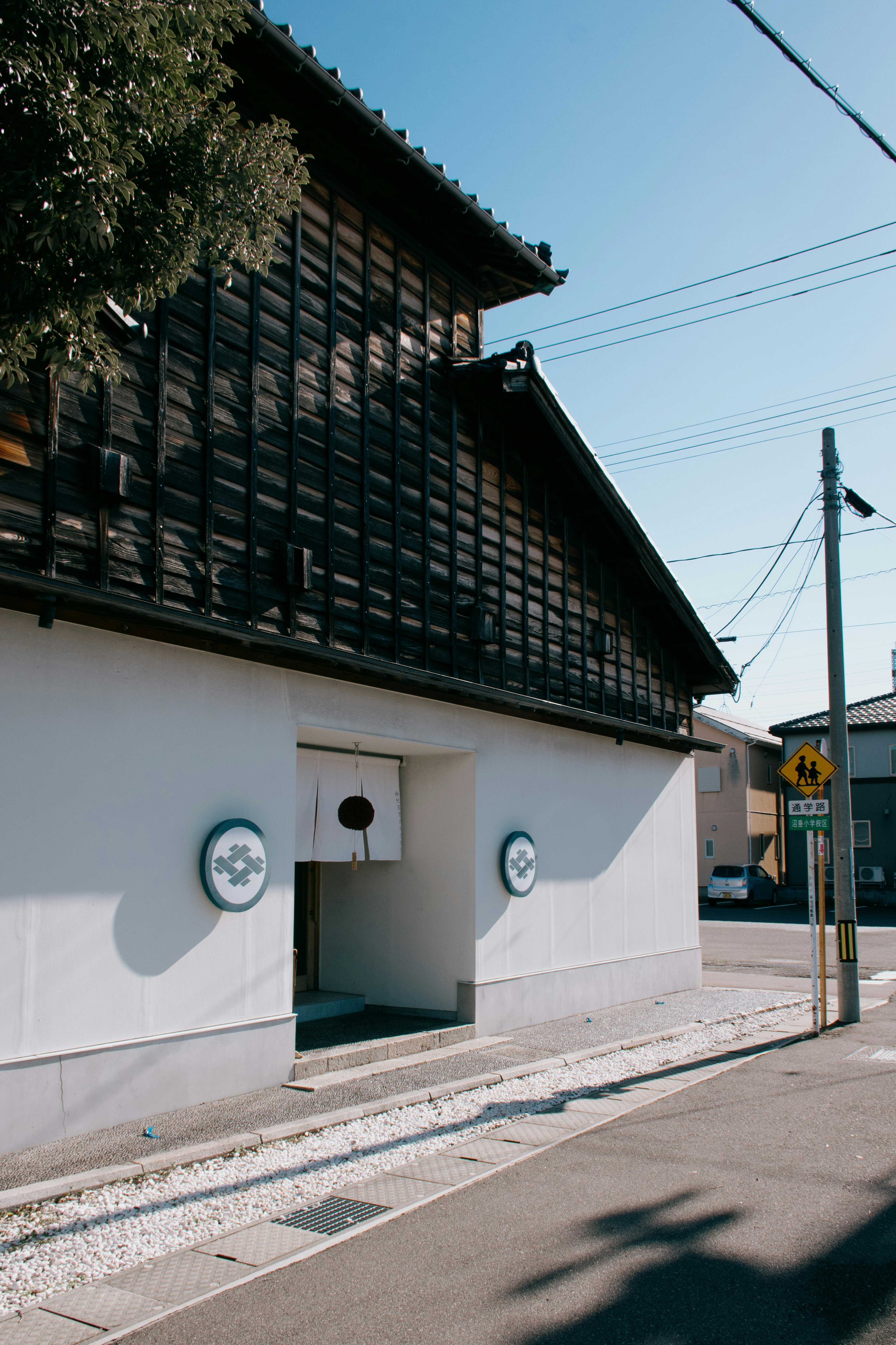 Exterior de un edificio japonés tradicional con techo de madera paredes blancas y símbolos circulares