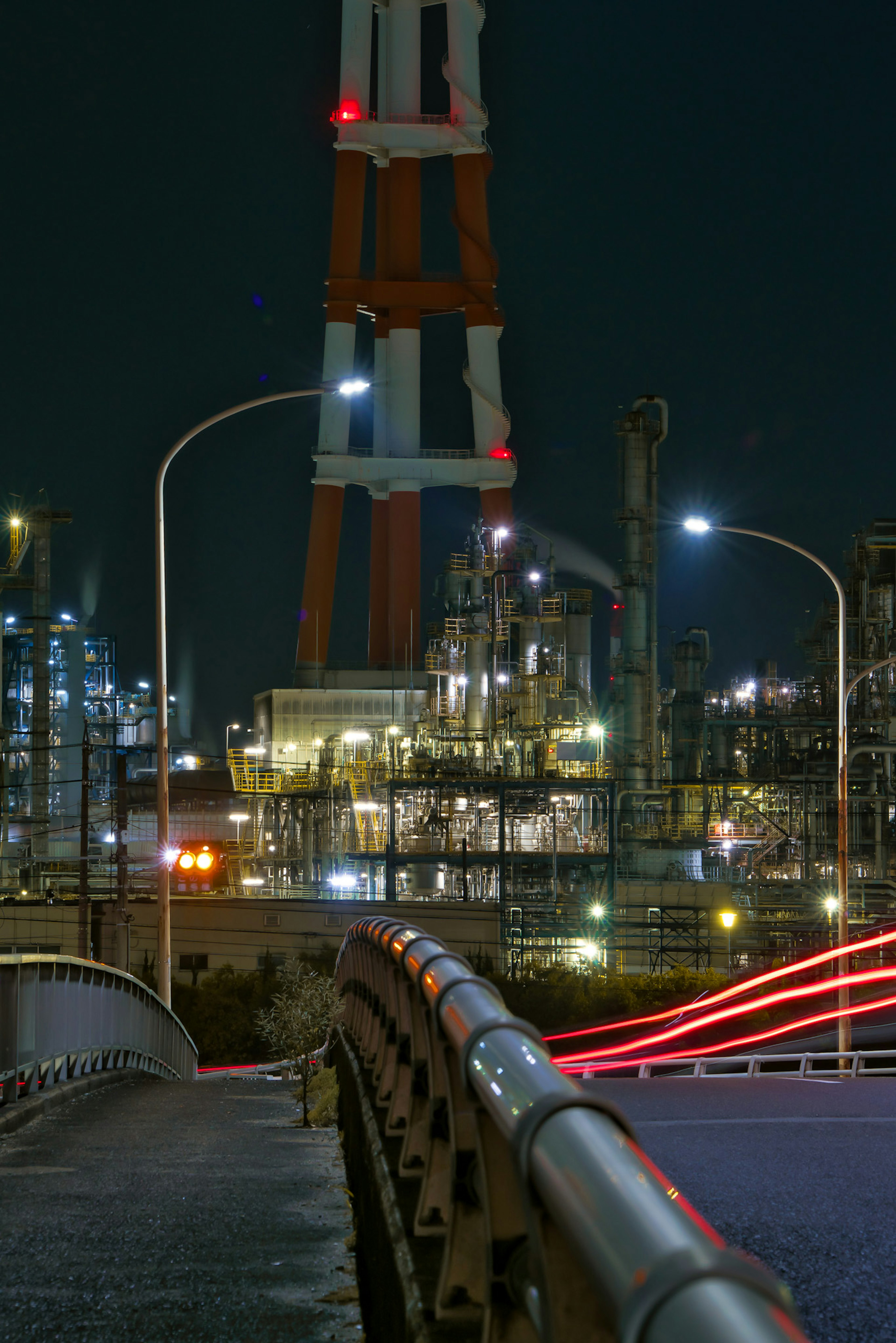 Night view of an industrial area with a bridge and smokestack