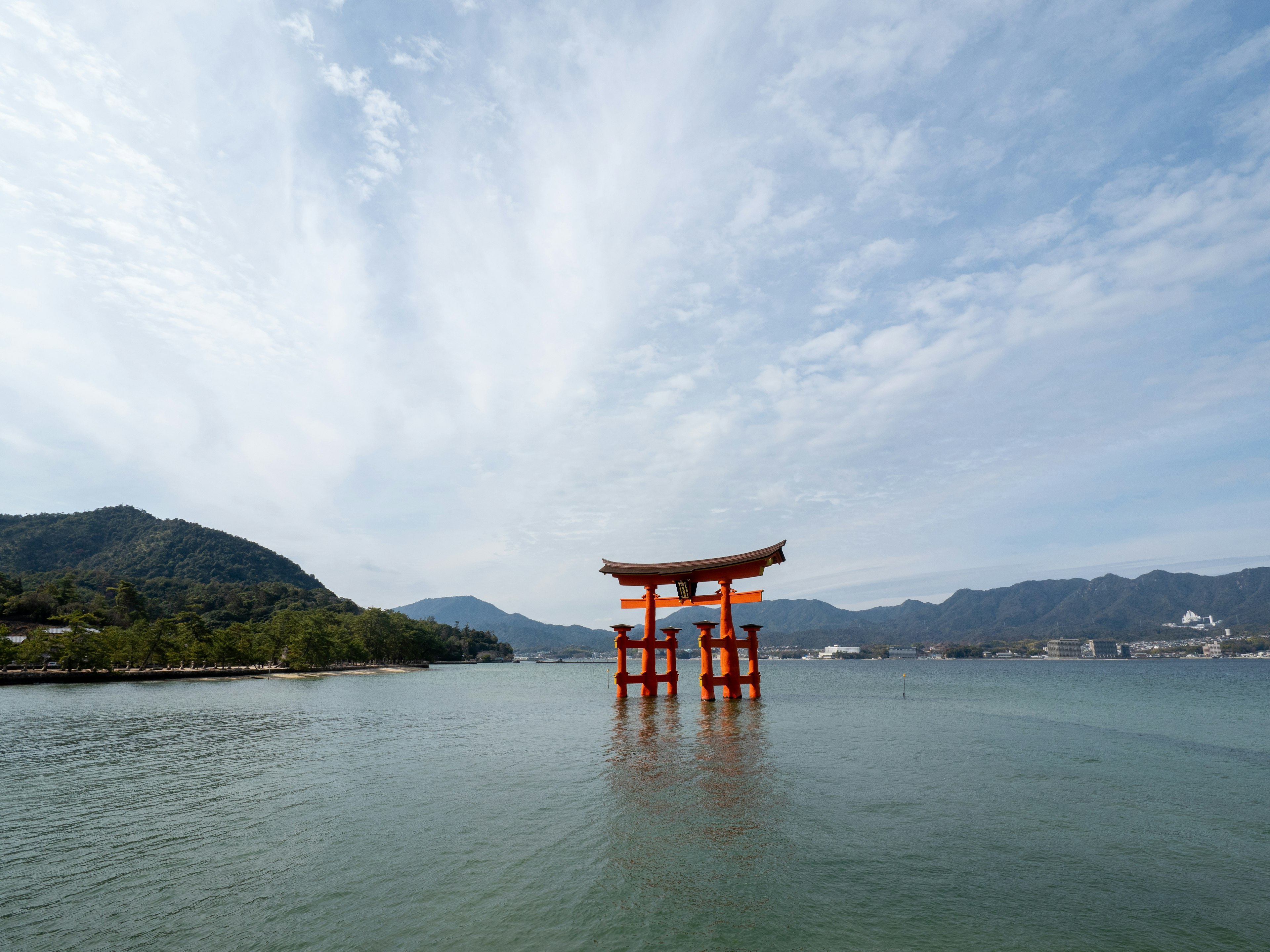 Cổng torii đỏ đứng trong nước dưới bầu trời xanh