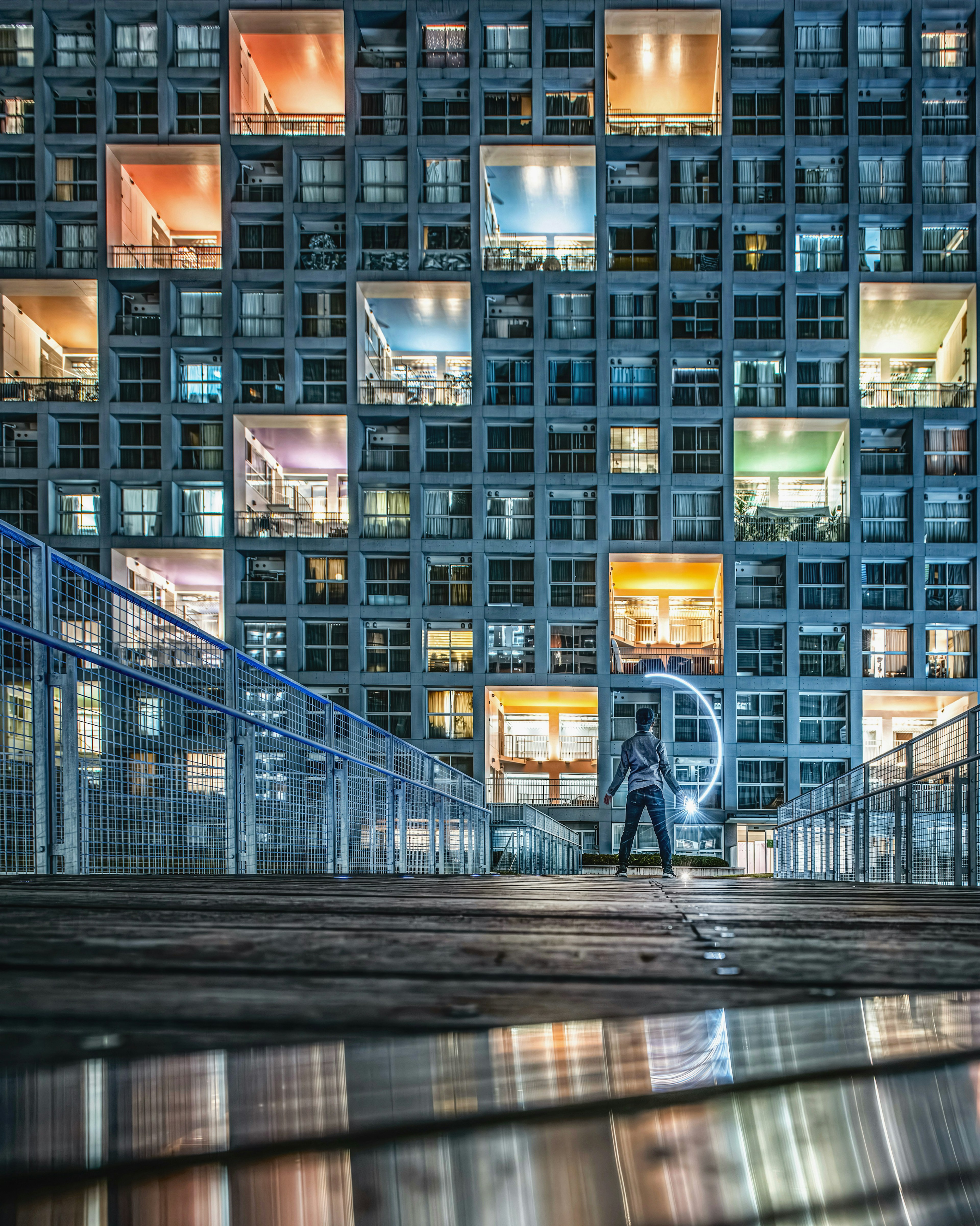 Una persona in piedi di fronte a un edificio moderno con finestre colorate di notte