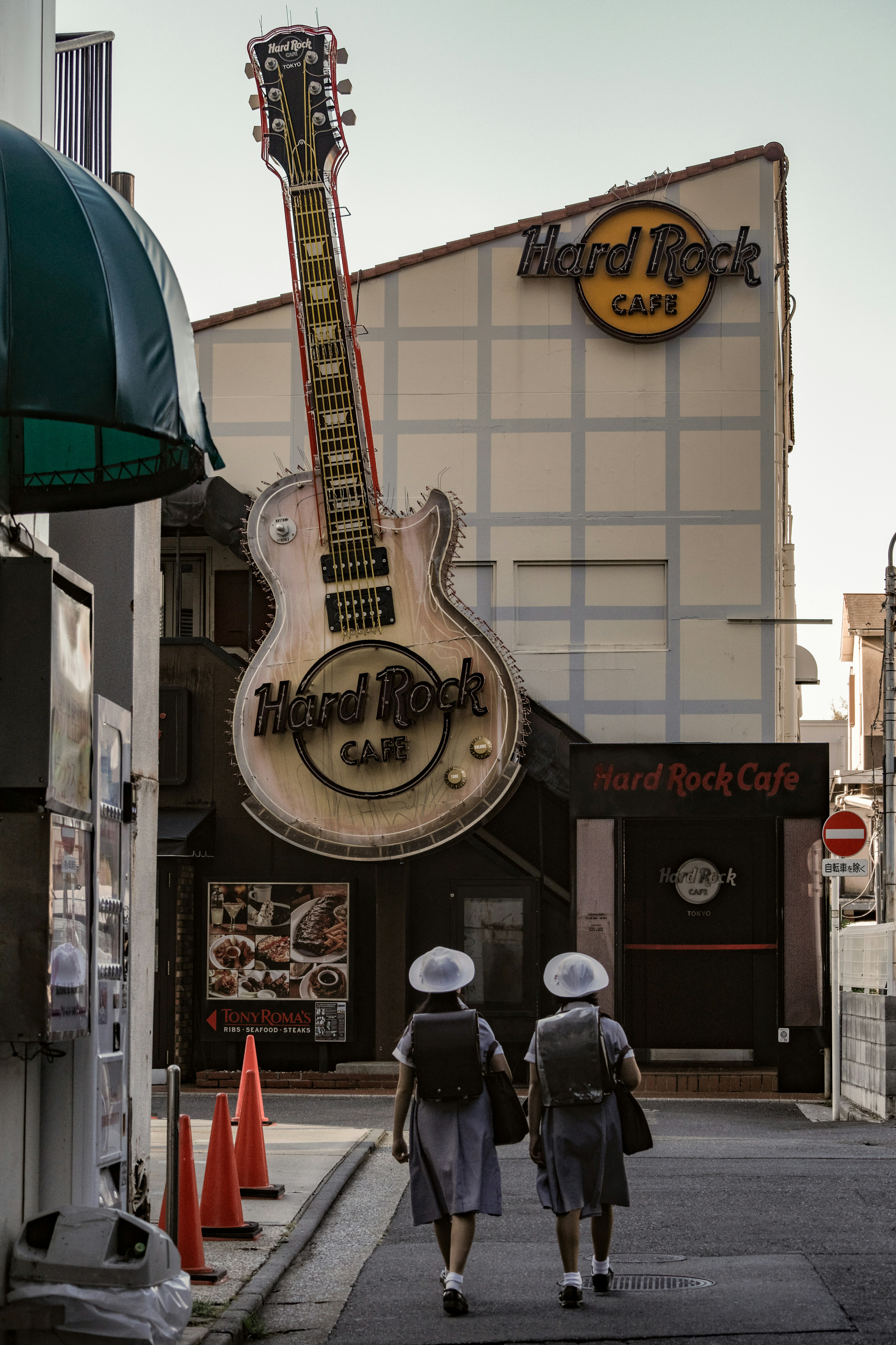 Dos estudiantes caminando junto a un letrero gigante de Hard Rock Cafe