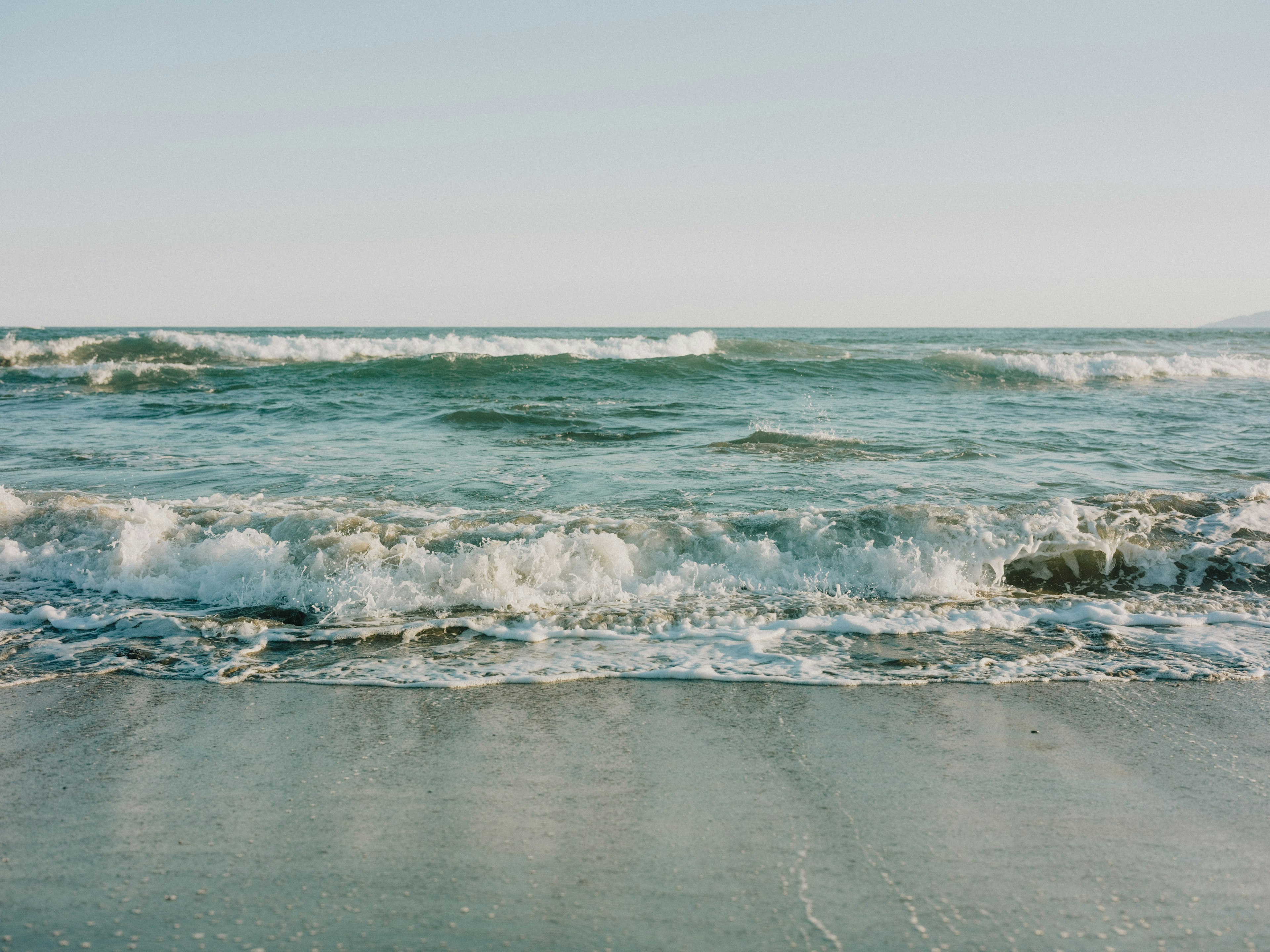 คลื่นทะเลที่นุ่มนวลซัดเข้าหาชายหาดทราย