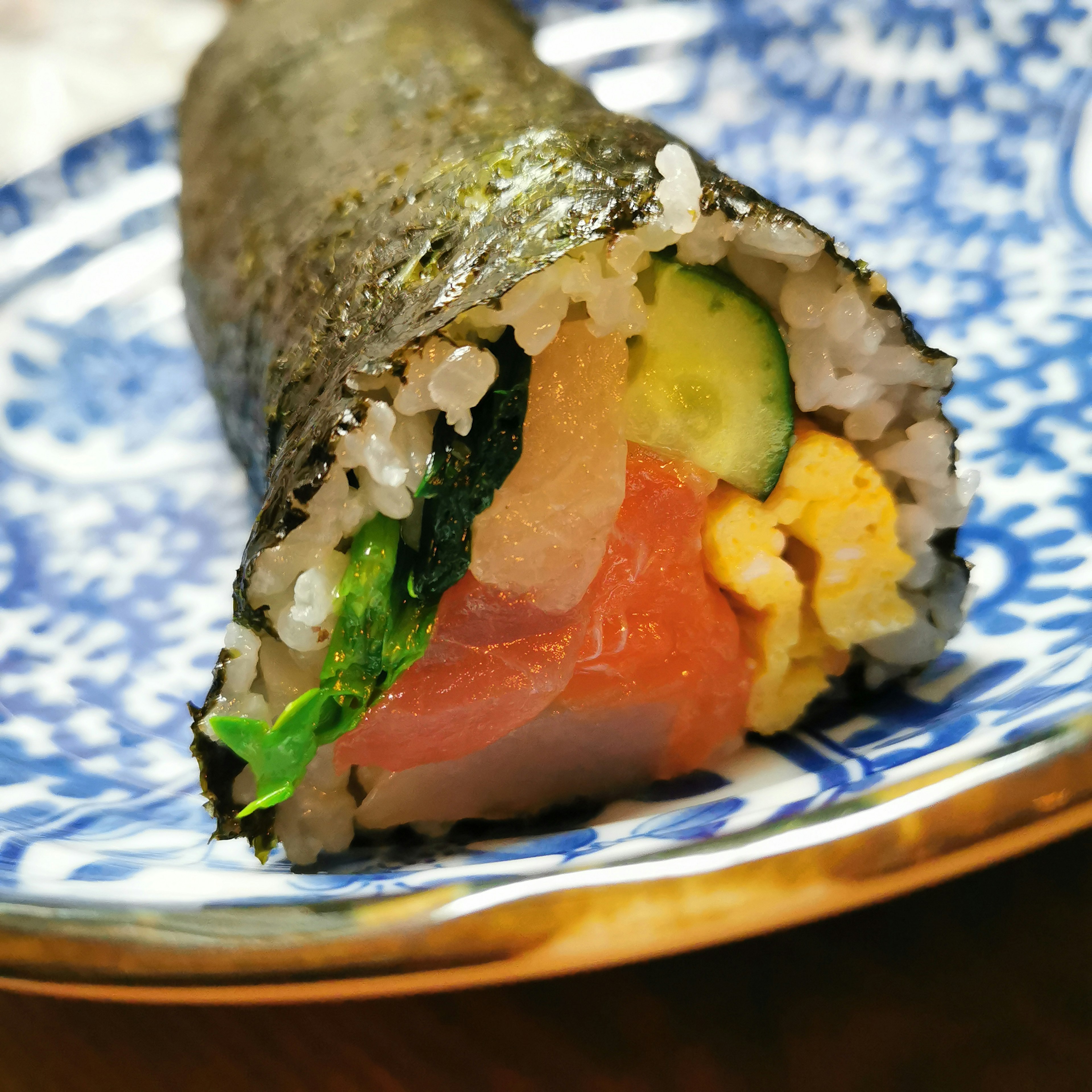 Colorful sushi roll filled with various ingredients on a beautiful blue plate