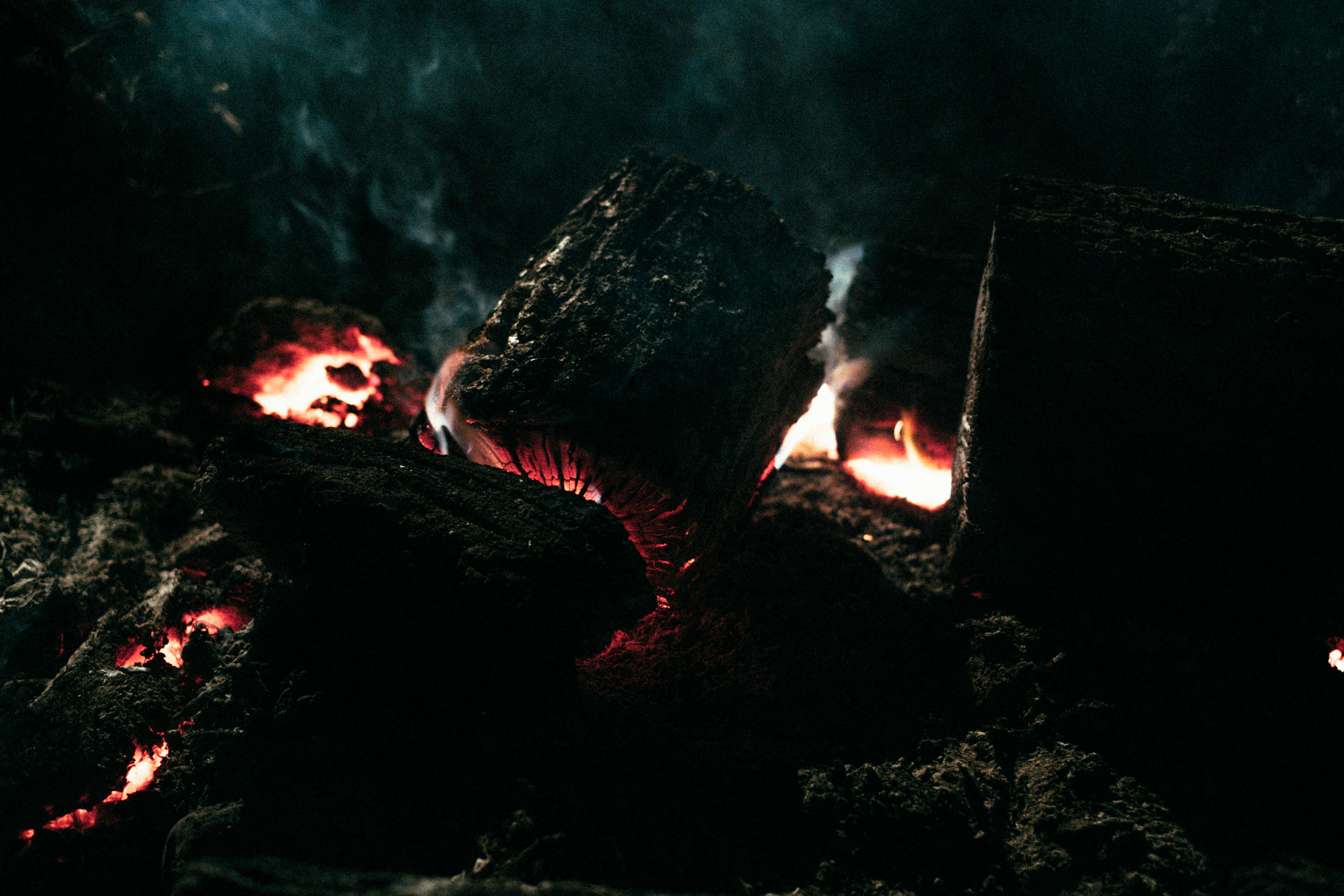 Kayu yang terbakar dengan api merah terlihat di latar belakang gelap