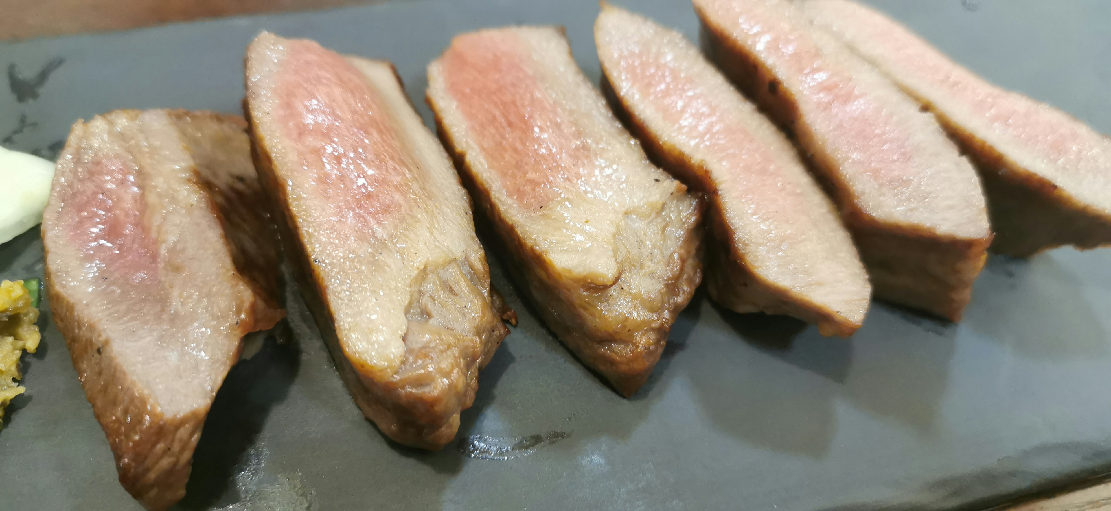 Viande tranchée disposée sur une assiette montrant une cuisson parfaite