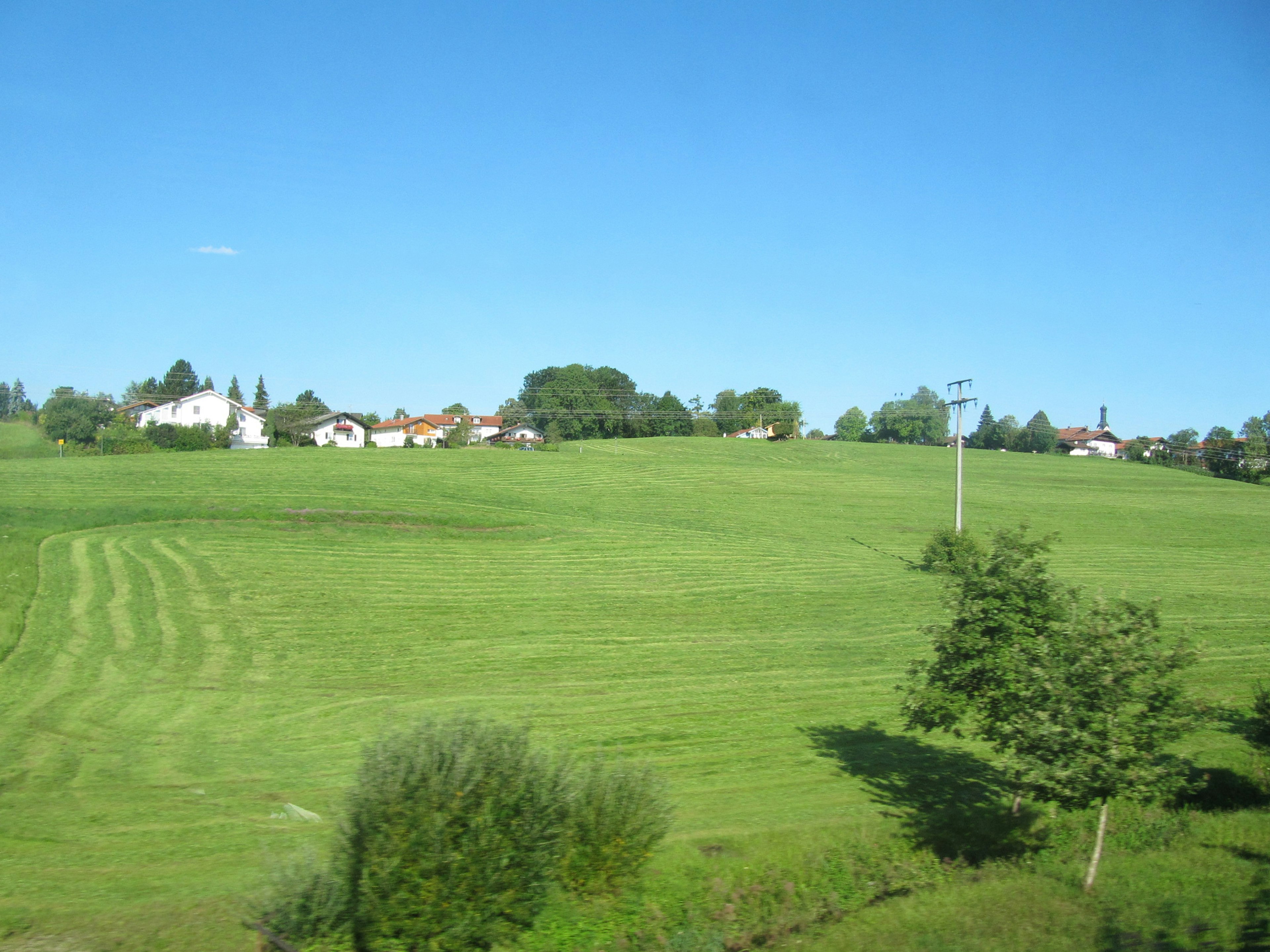 Eine Landschaft mit grünen Feldern und Häusern unter einem blauen Himmel