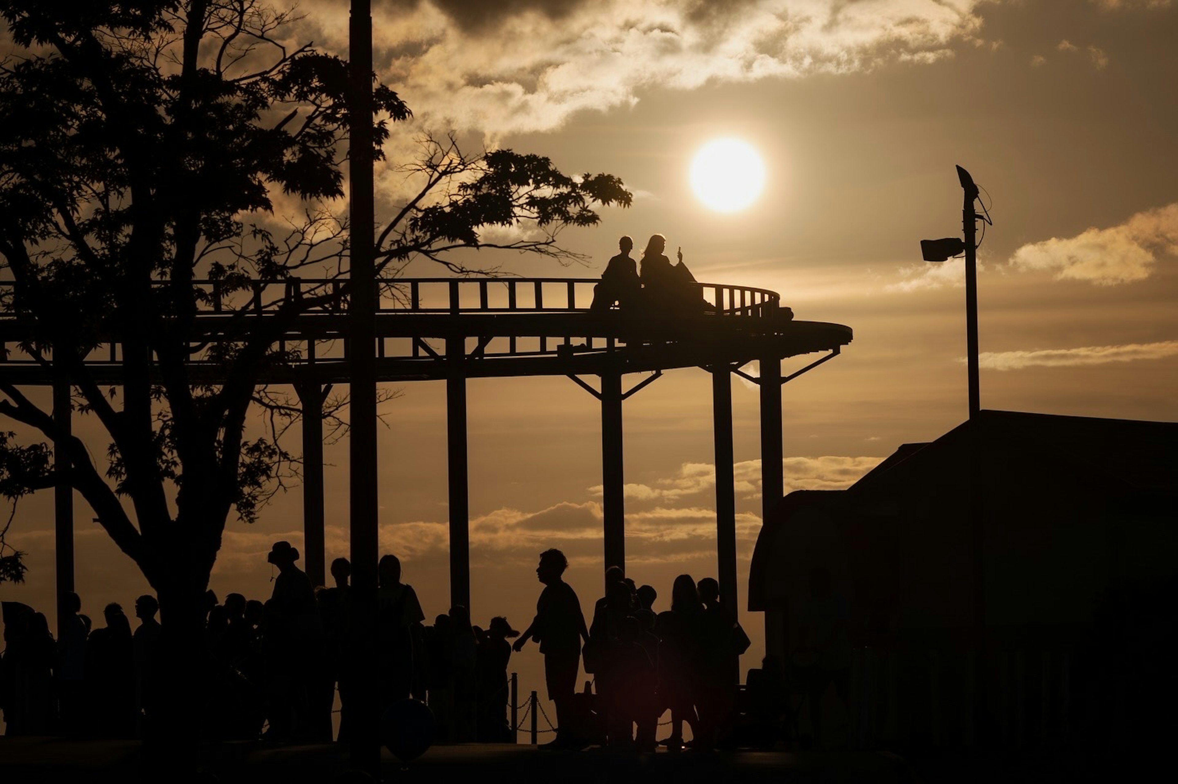 Silueta de una noria y personas al atardecer