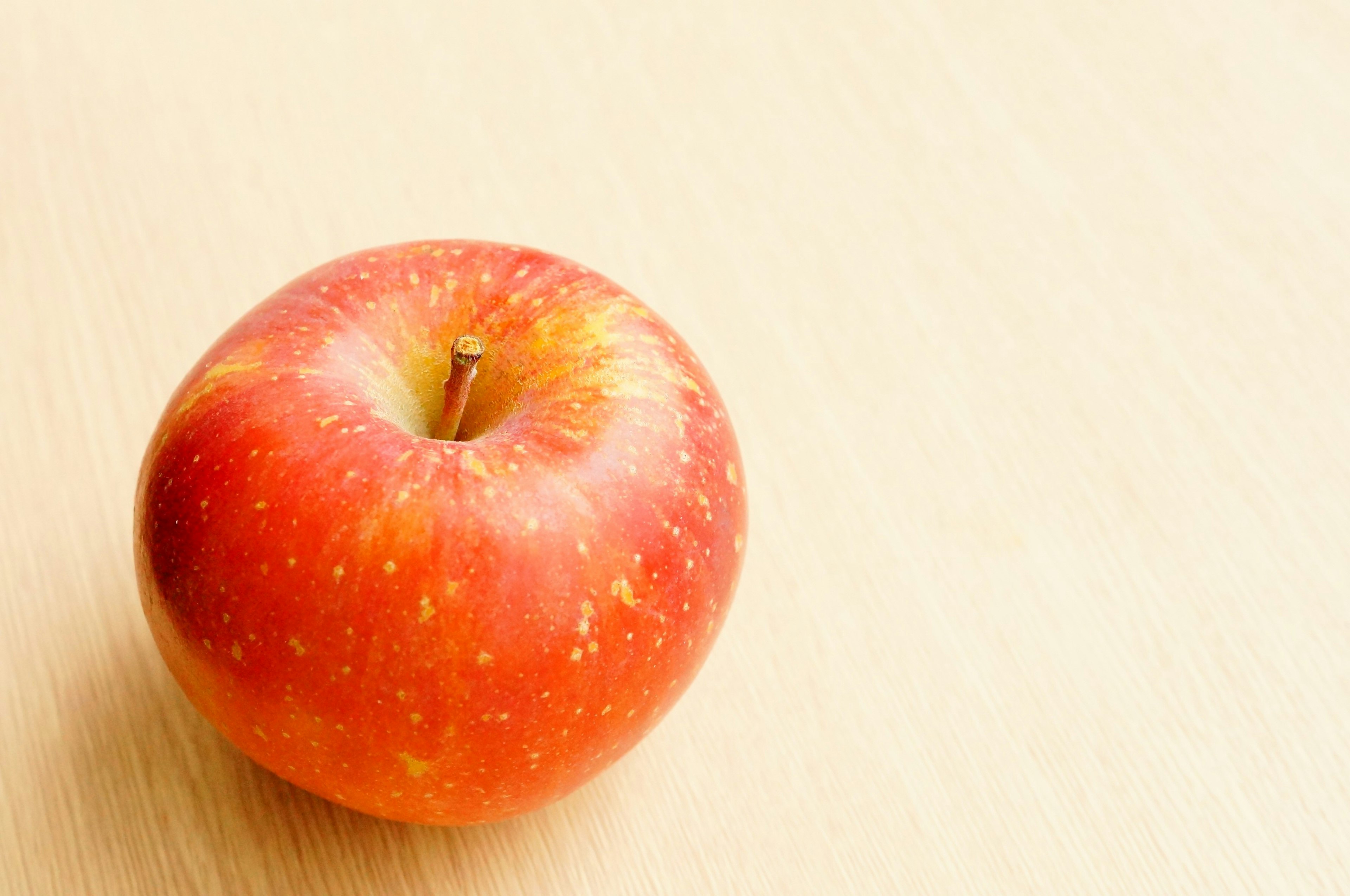 A red apple resting on a wooden table