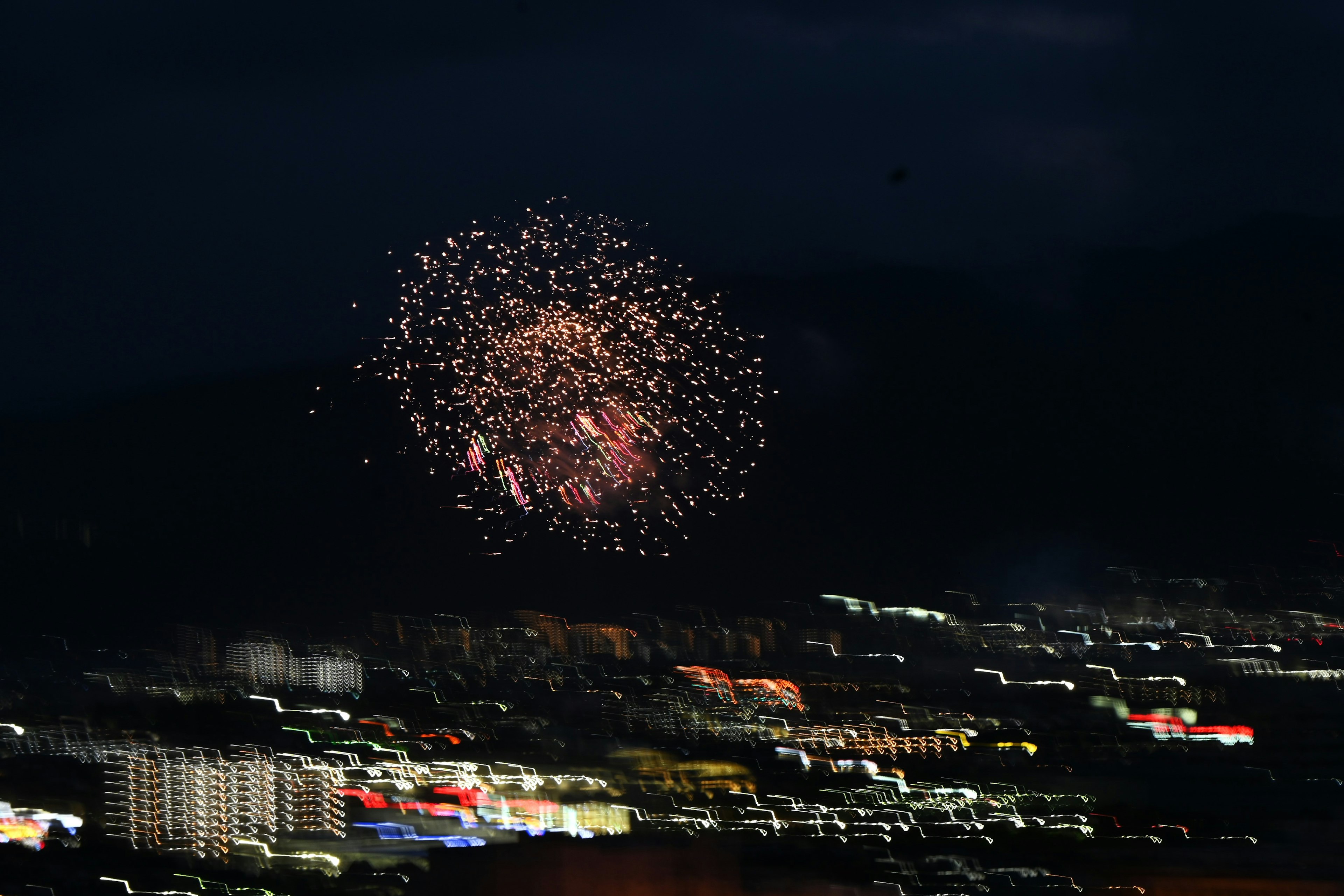 Fuegos artificiales estallando en el cielo nocturno sobre un horizonte urbano