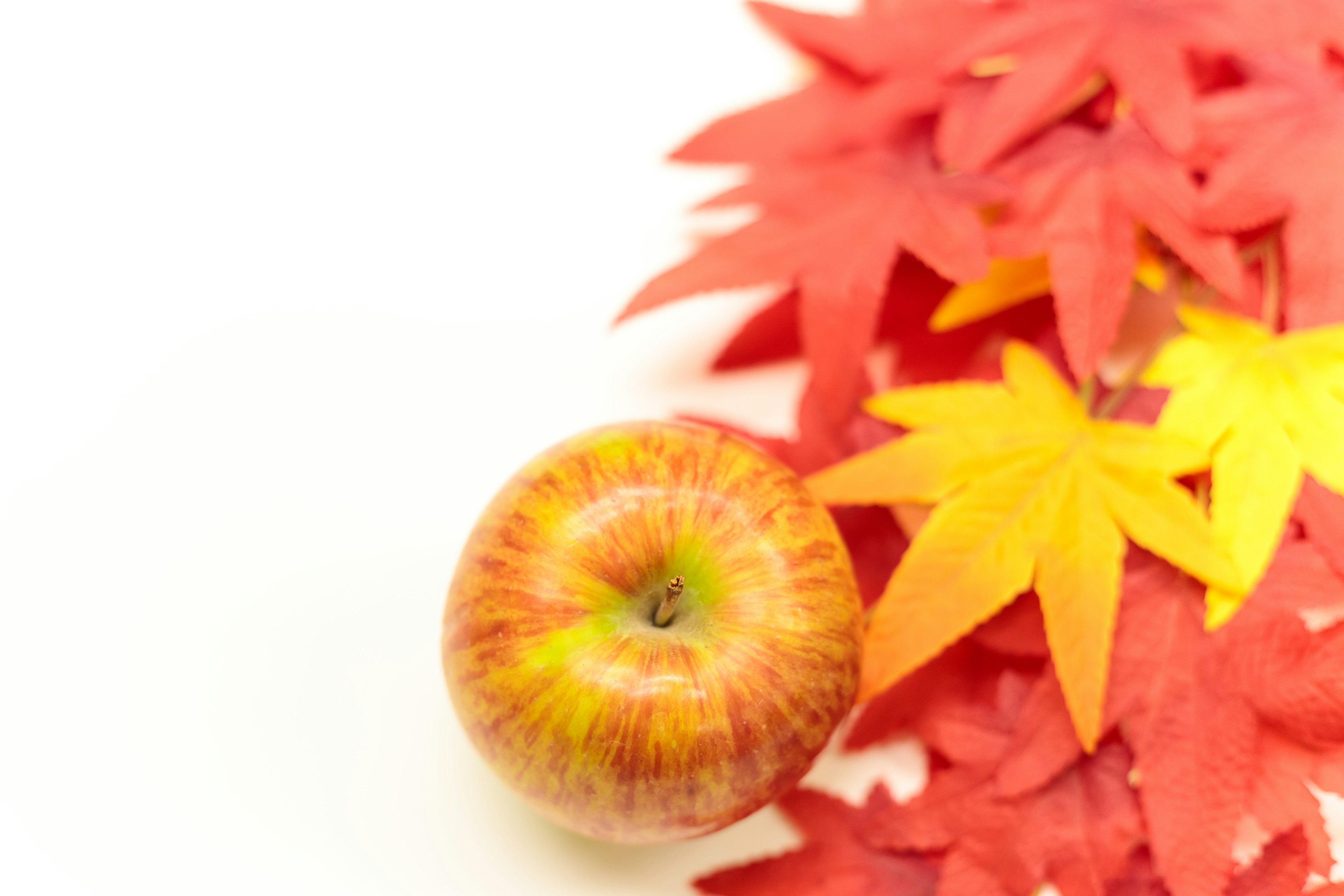 Una manzana sobre hojas de otoño rojas y amarillas