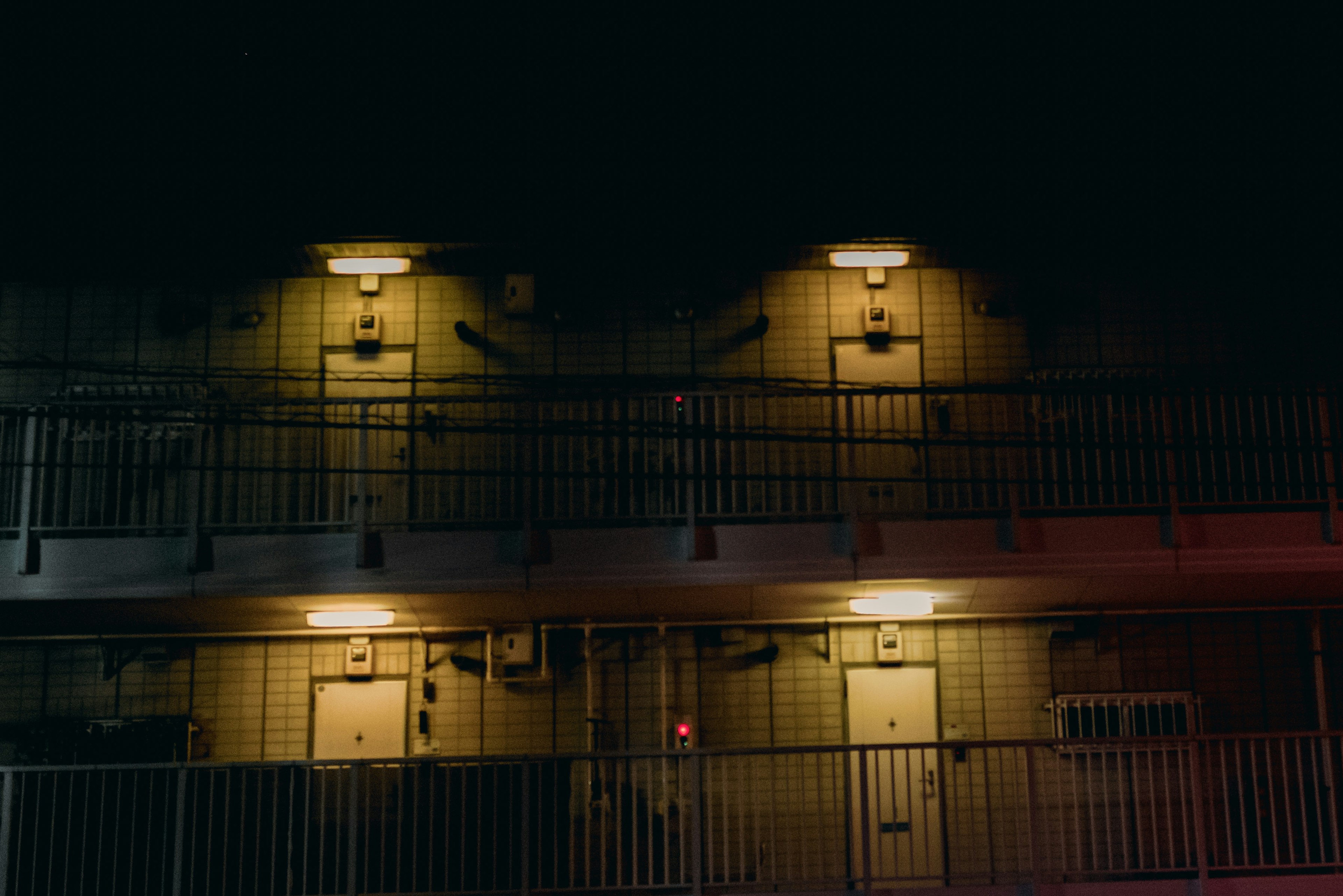 Extérieur d'un motel illuminé la nuit avec deux niveaux de balcons et de portes