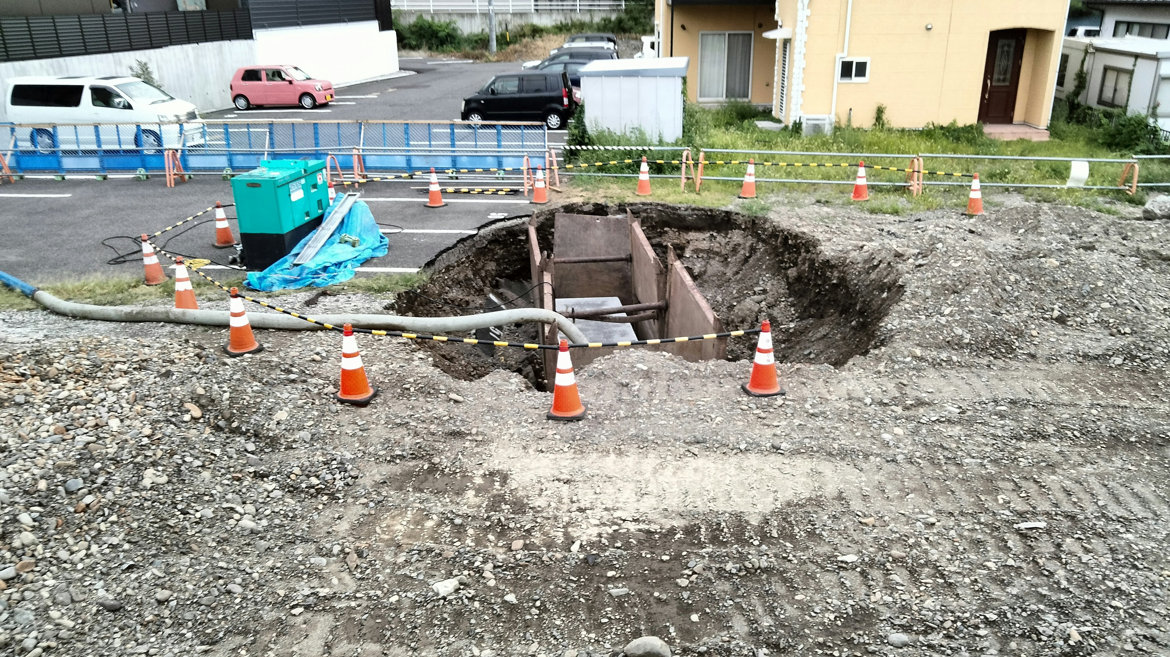 Construction site with a large hole surrounded by traffic cones and machinery