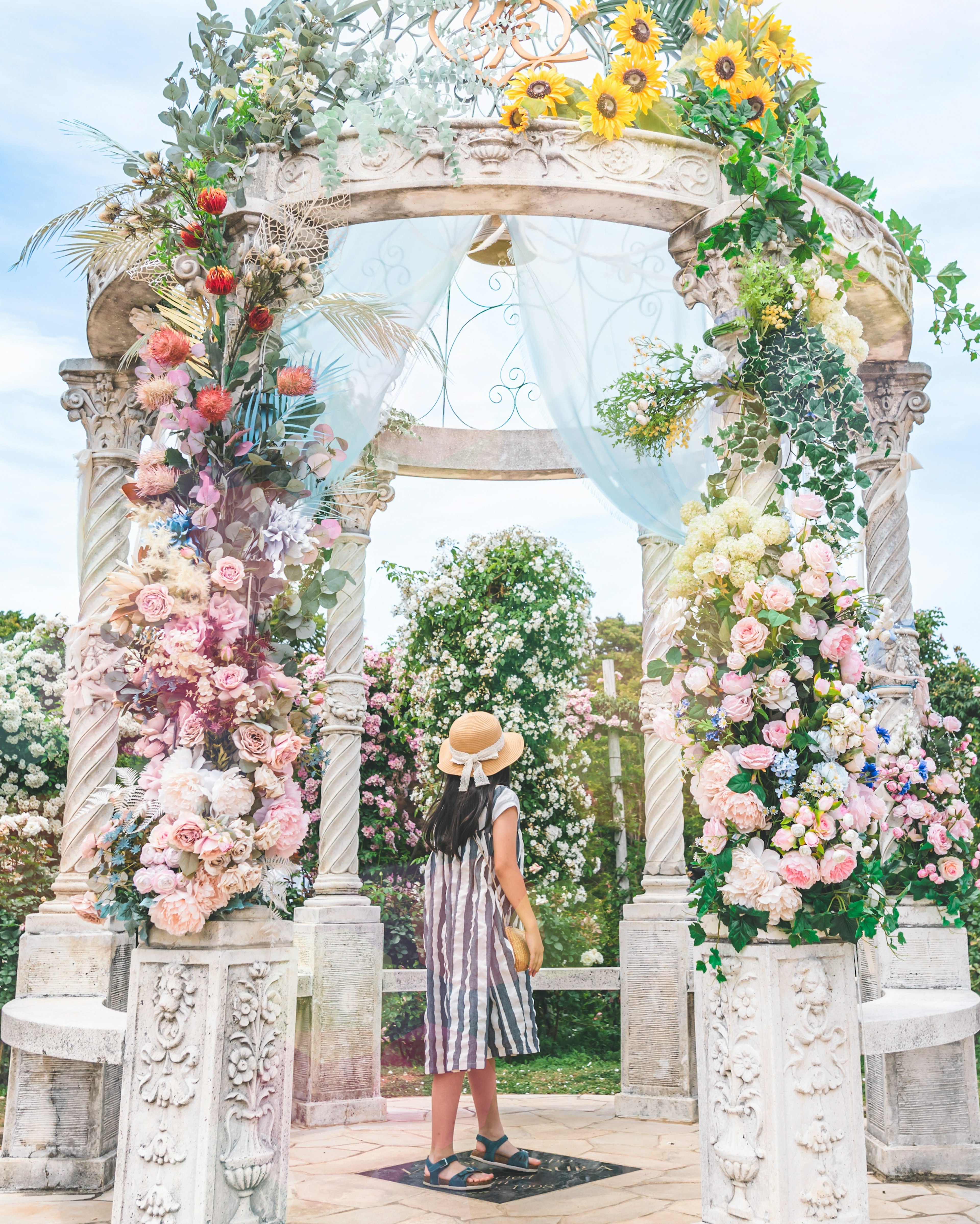 A woman standing in front of a flower-adorned gazebo